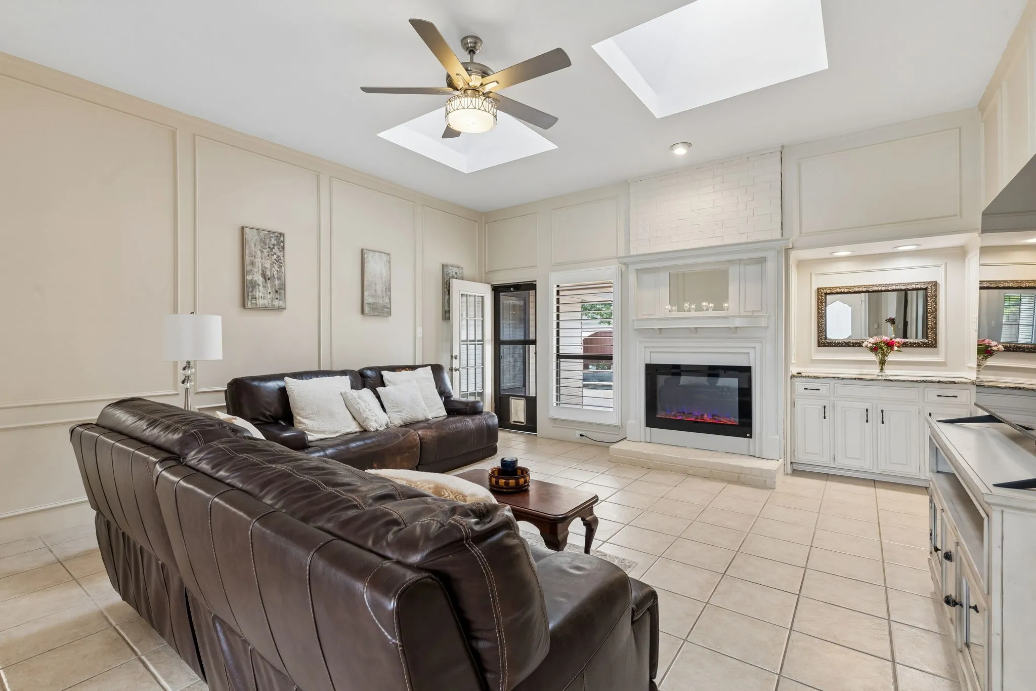 Huge living room with high ceiling, skylights, antique mantle and view to the pool.
