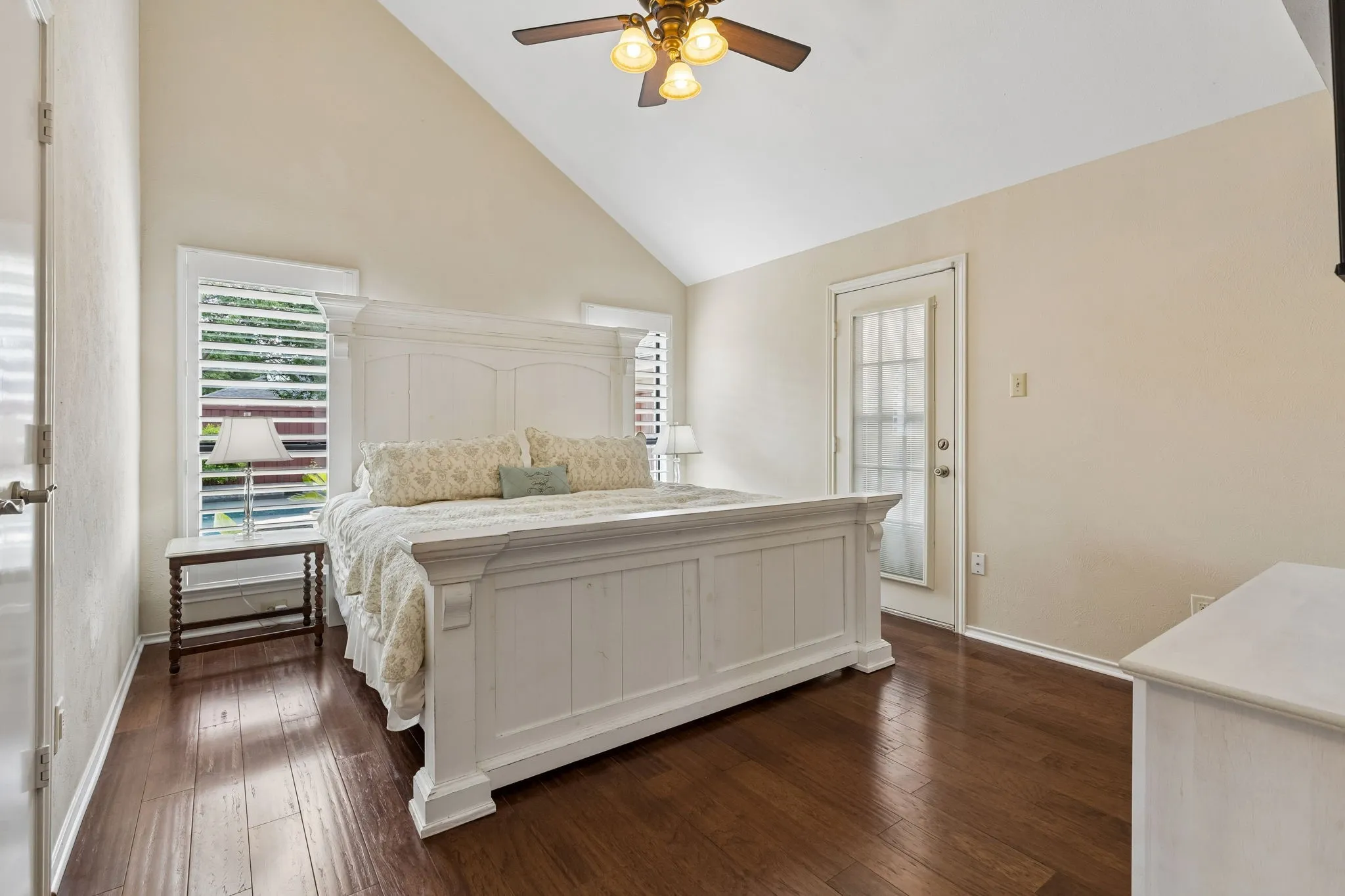 Primary bedroom with high ceiling, real hard wood floor, plantation shutters and a second door to the patio.