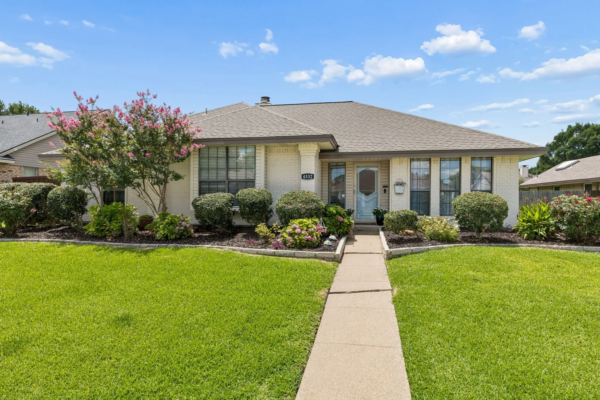 Front view with extensive landscaping and stone edging.