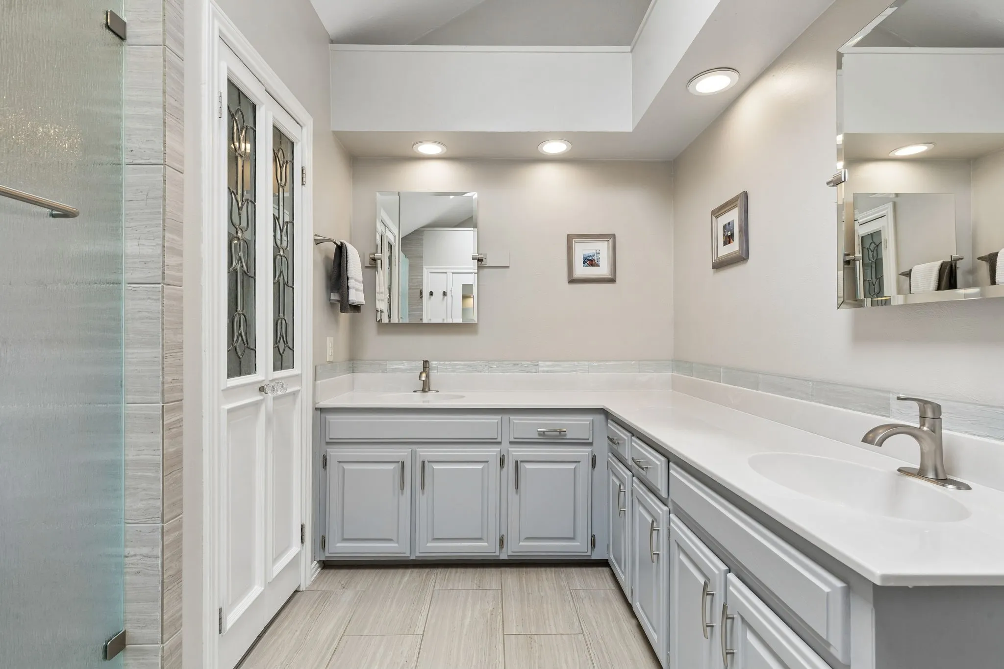 Another view of the primary bedroom with two vanities and lots of storage cabinets.