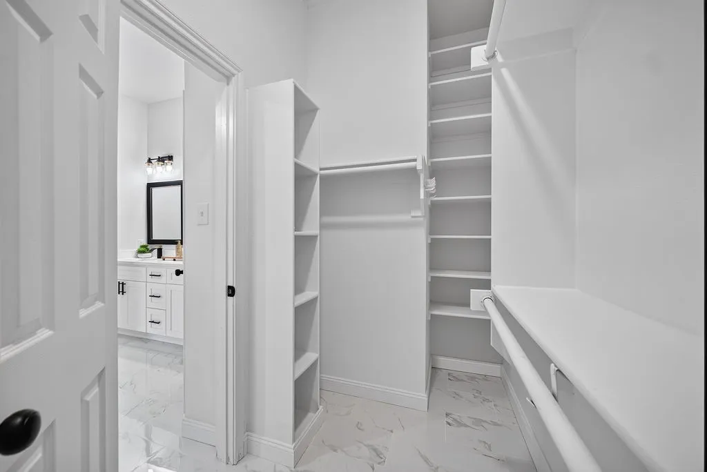 Walk-in closet featuring extensive built-in shelving and hanging rods