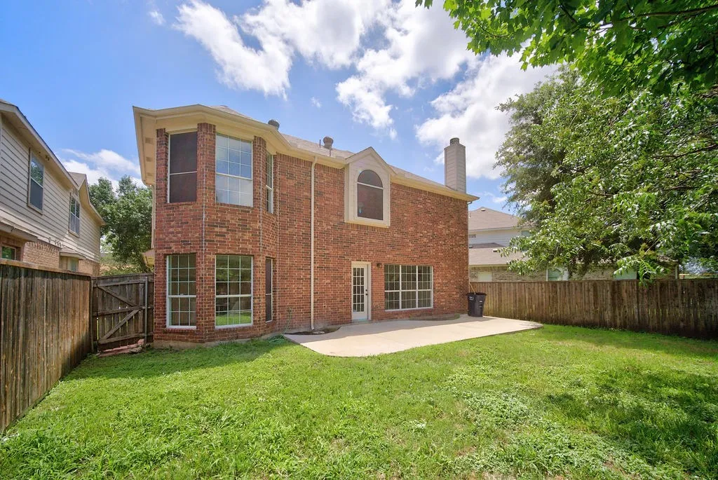 Rear brick exterior featuring multiple windows and a curved patio