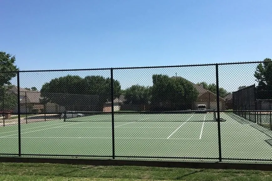 Regulation-size tennis court featuring a green playing surface and white boundary lines