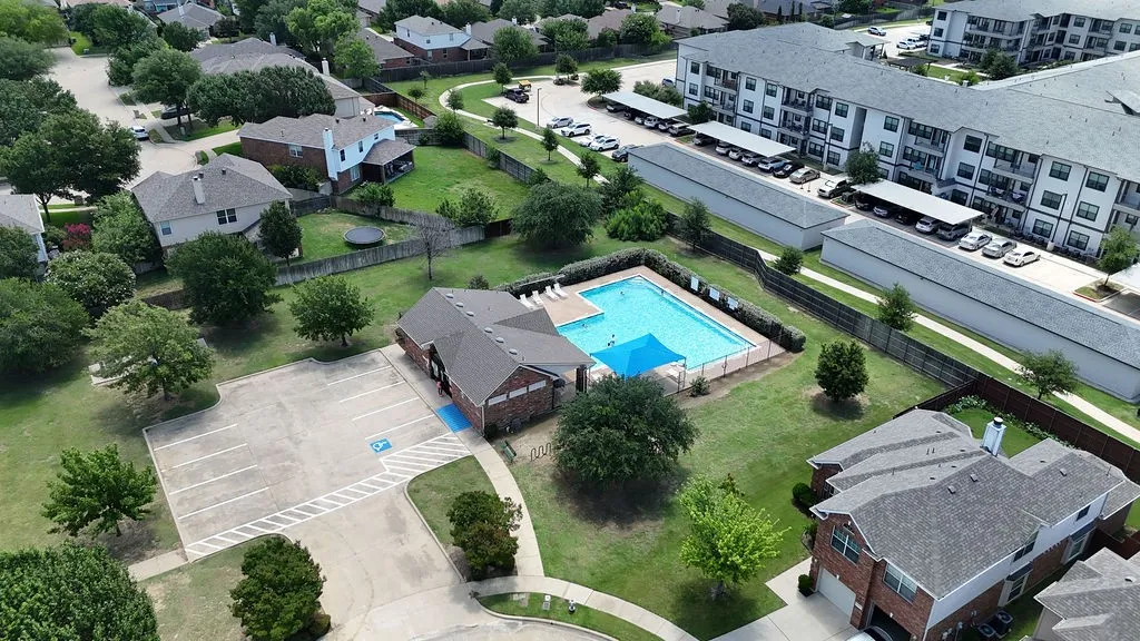 Community amenity building featuring an outdoor swimming pool, surrounding lounge area, and dedicated parking lot