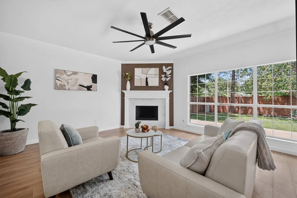 Living area featuring a fireplace with a white mantel and marble surround, wood-finish flooring, and a contemporary ceiling fan