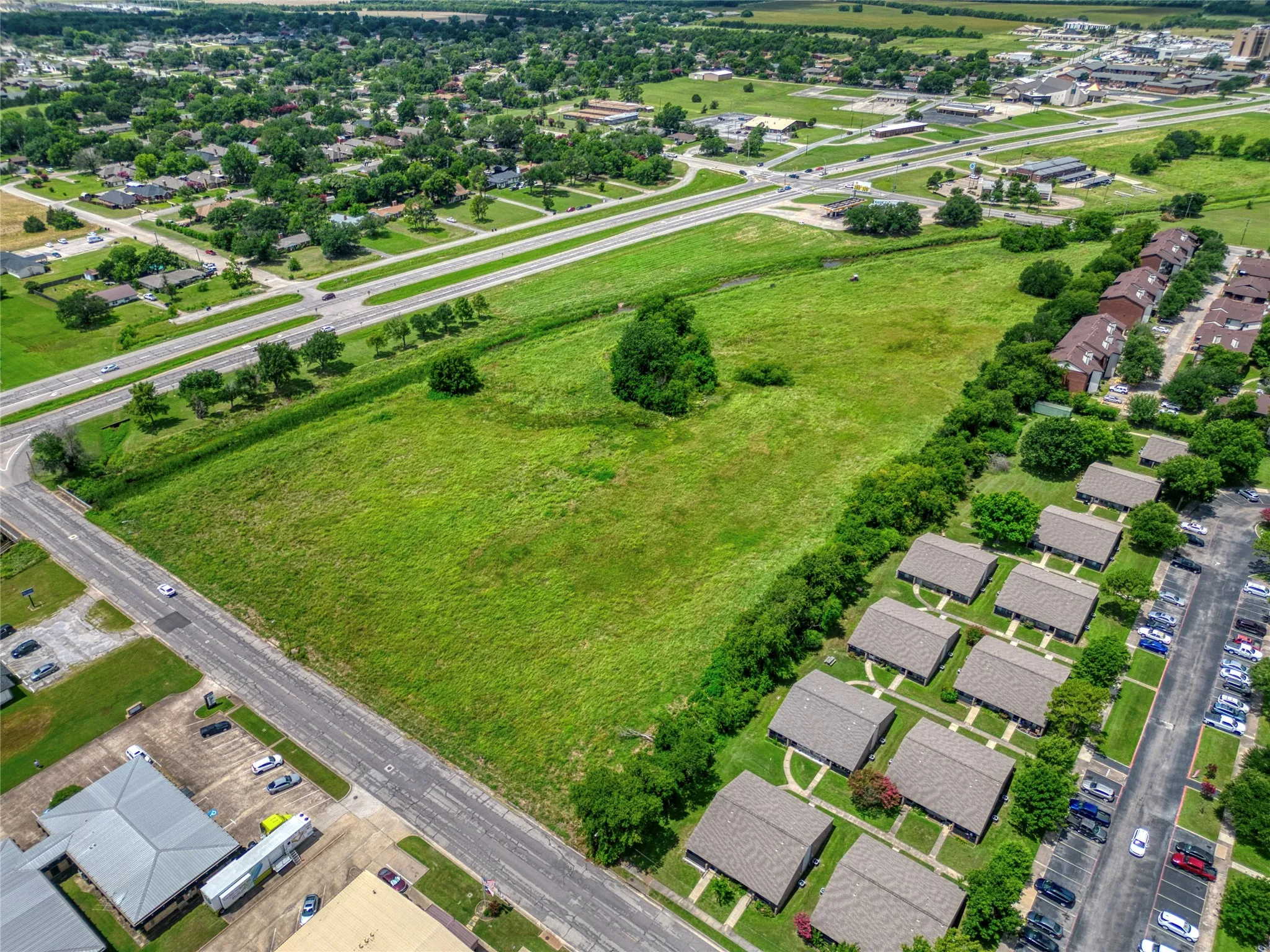 Expansive green space featuring mature trees and bordering a multi-lane roadway