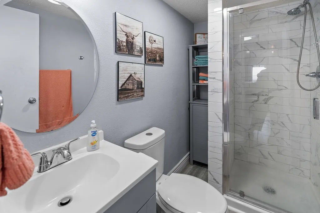 The full hall bath is between bedrooms 2 and 3 and features a tiled glass-door shower.