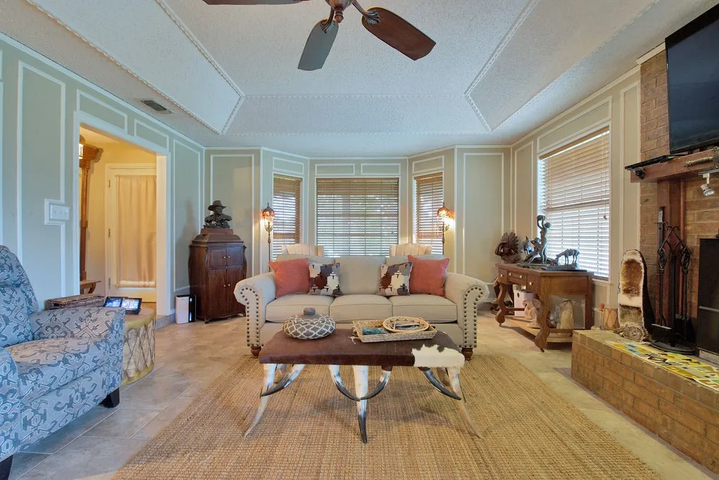 Spacious living area featuring tile flooring, a tray ceiling, and a ceiling fan
