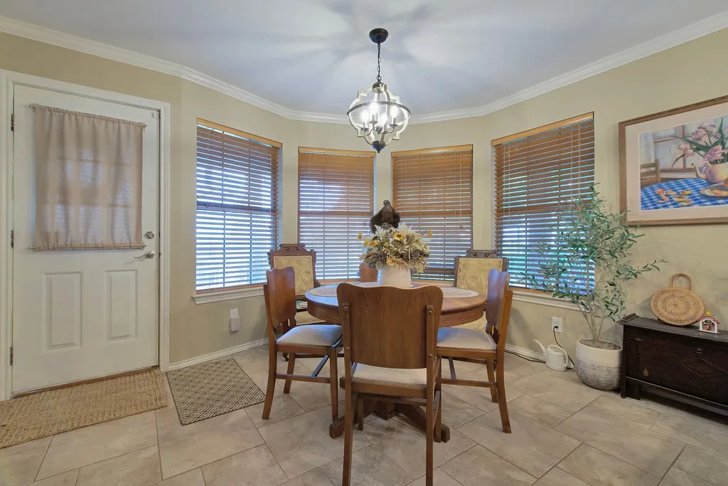 Dining area featuring a bay window with natural wood blinds, a chandelier, and tile flooring