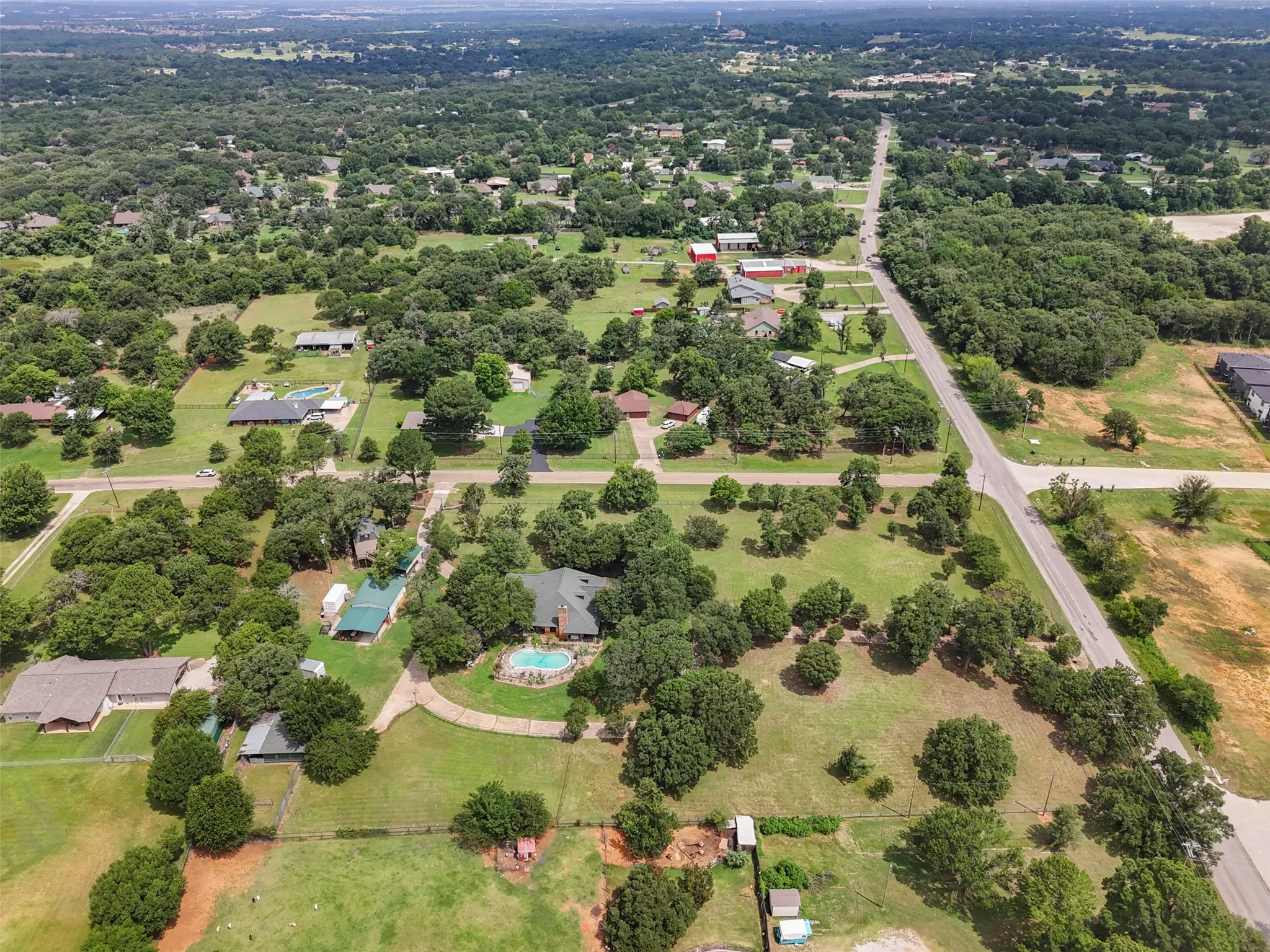 Sprawling home out of City Limits, featuring numerous mature trees and expansive green spaces.