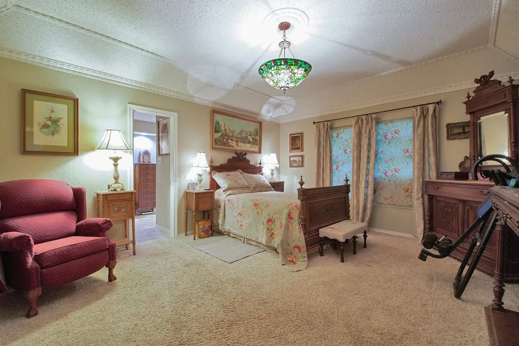 Carpeted room featuring a ceiling medallion with a Tiffany-style pendant light, crown molding, and two windows with drapes