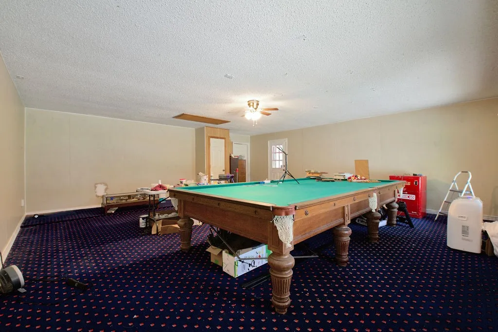 Spacious room with patterned carpet flooring, light-toned walls, and a textured ceiling