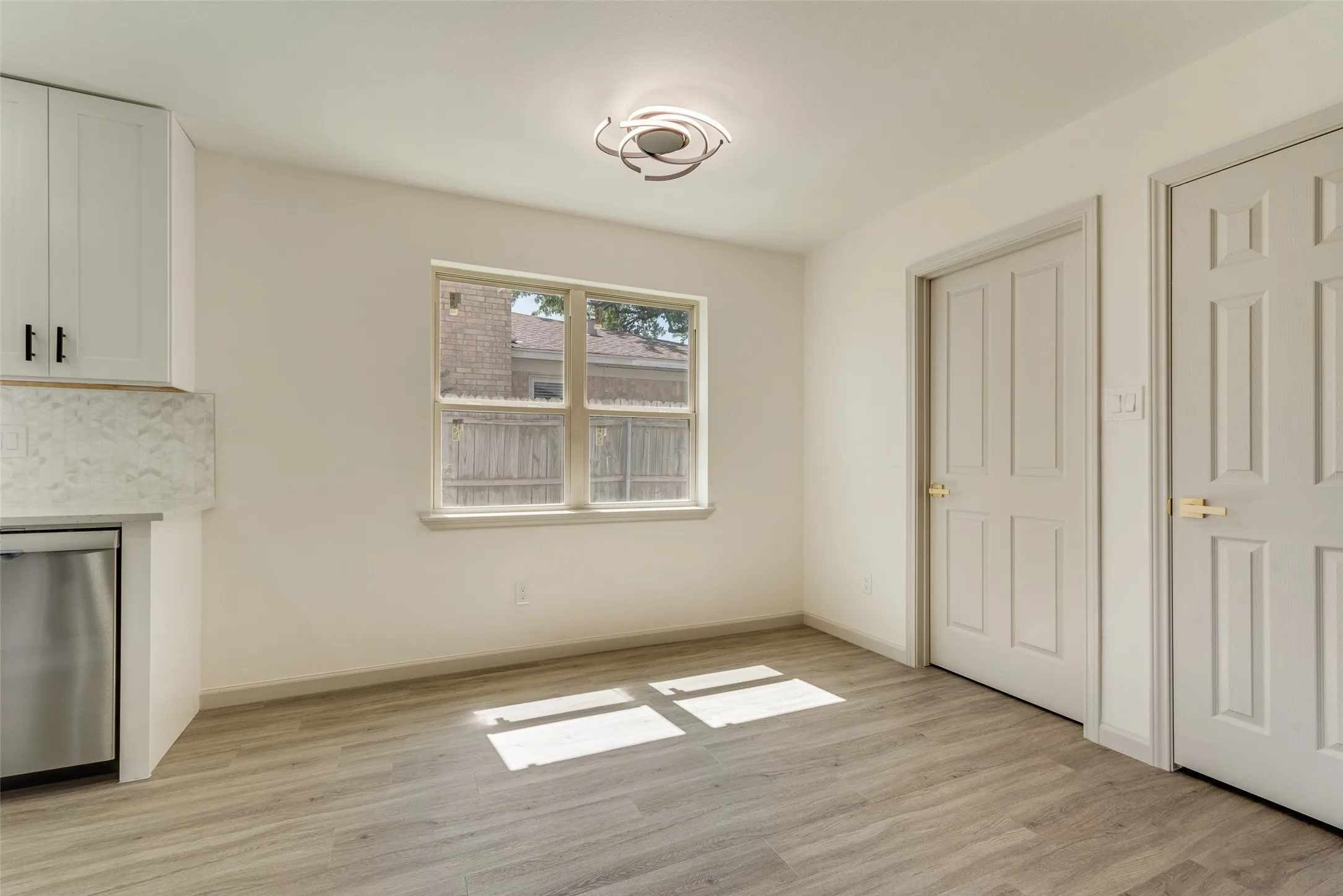 Bright interior space featuring wood-finish flooring, white walls, and a modern ceiling light fixture