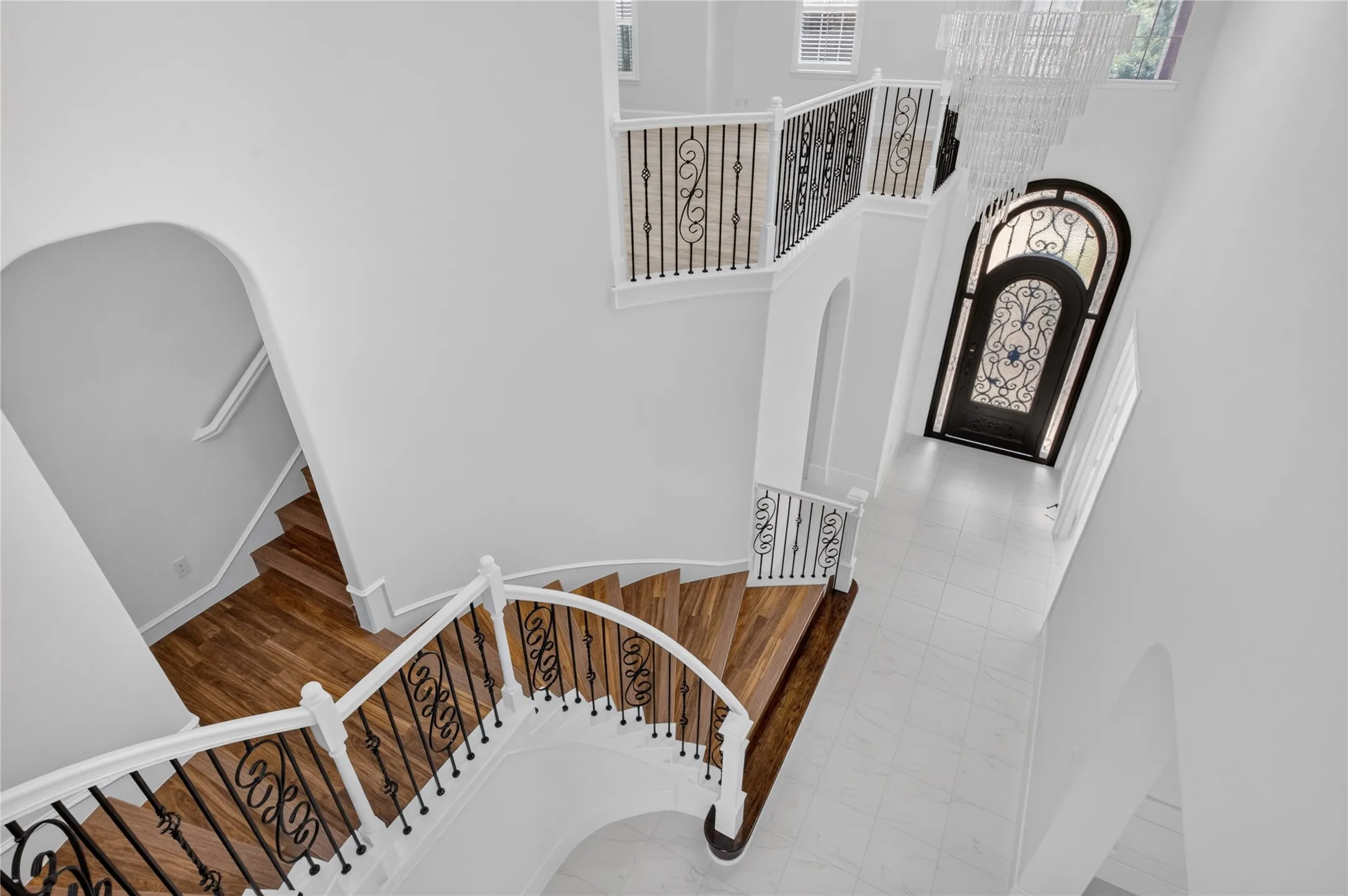Grand entryway featuring a decorative arch-top door with intricate ironwork and a sweeping staircase