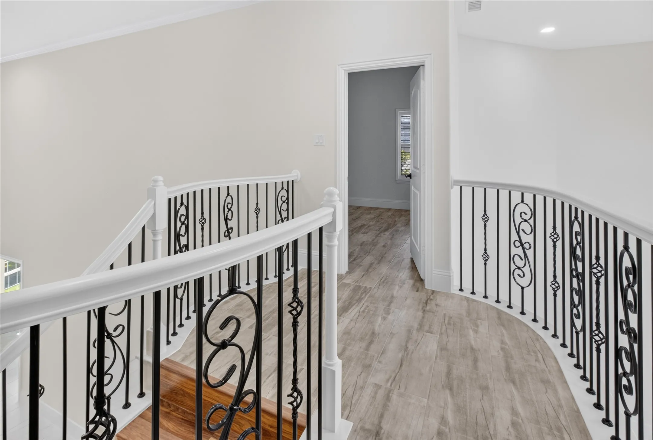 Curved upper landing with wood-finish flooring and white walls