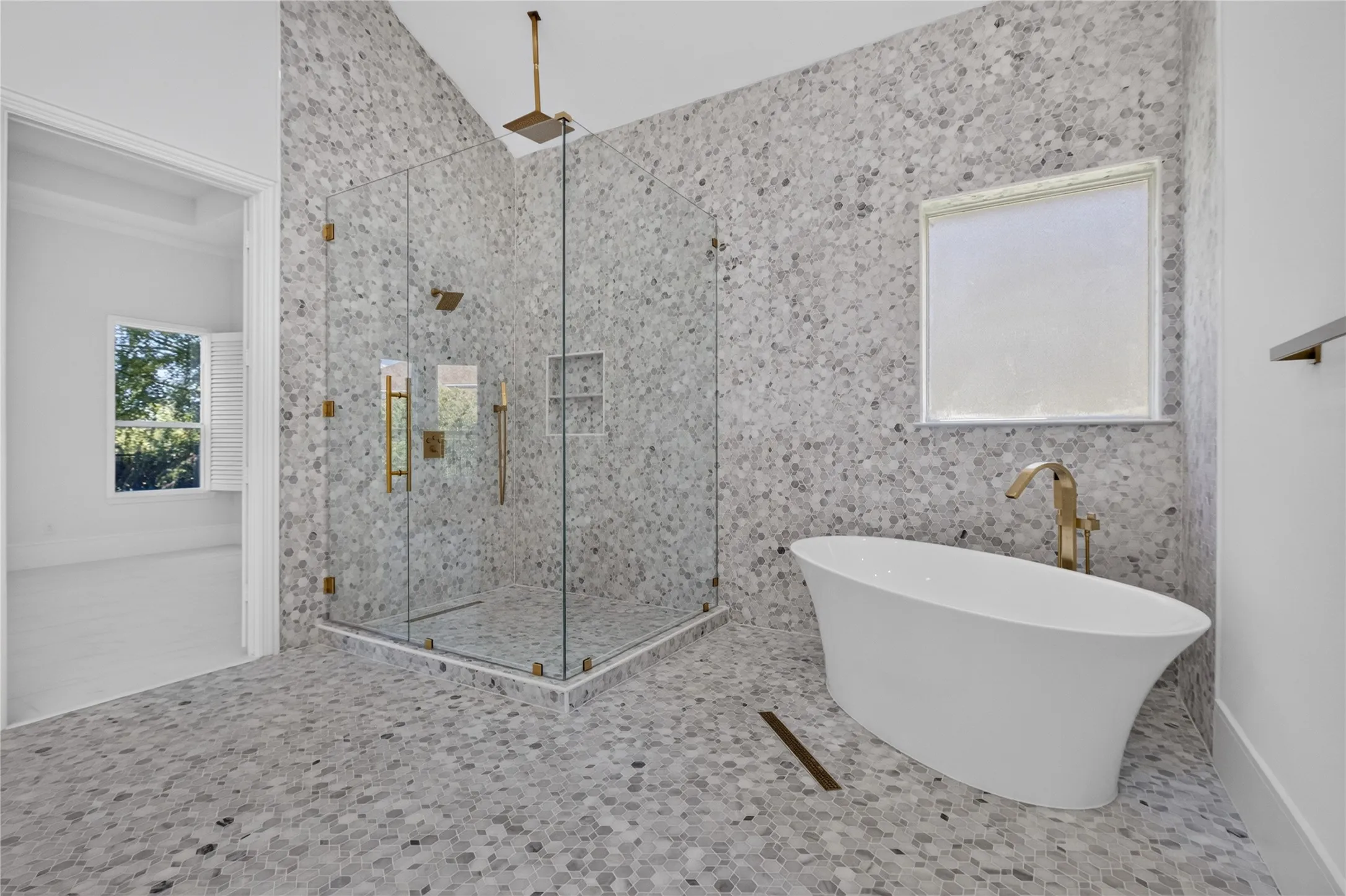 Spacious bathroom featuring a frameless glass shower enclosure, a freestanding soaking tub, and mosaic tile flooring