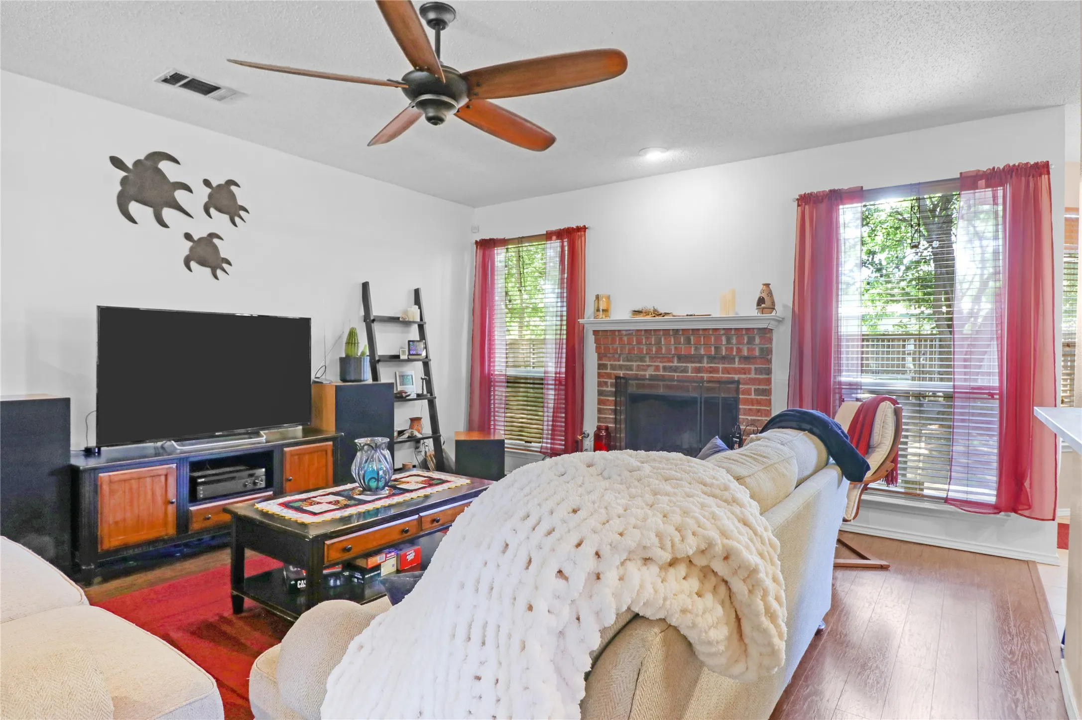 Living room with view of back yard and wood burning fireplace.