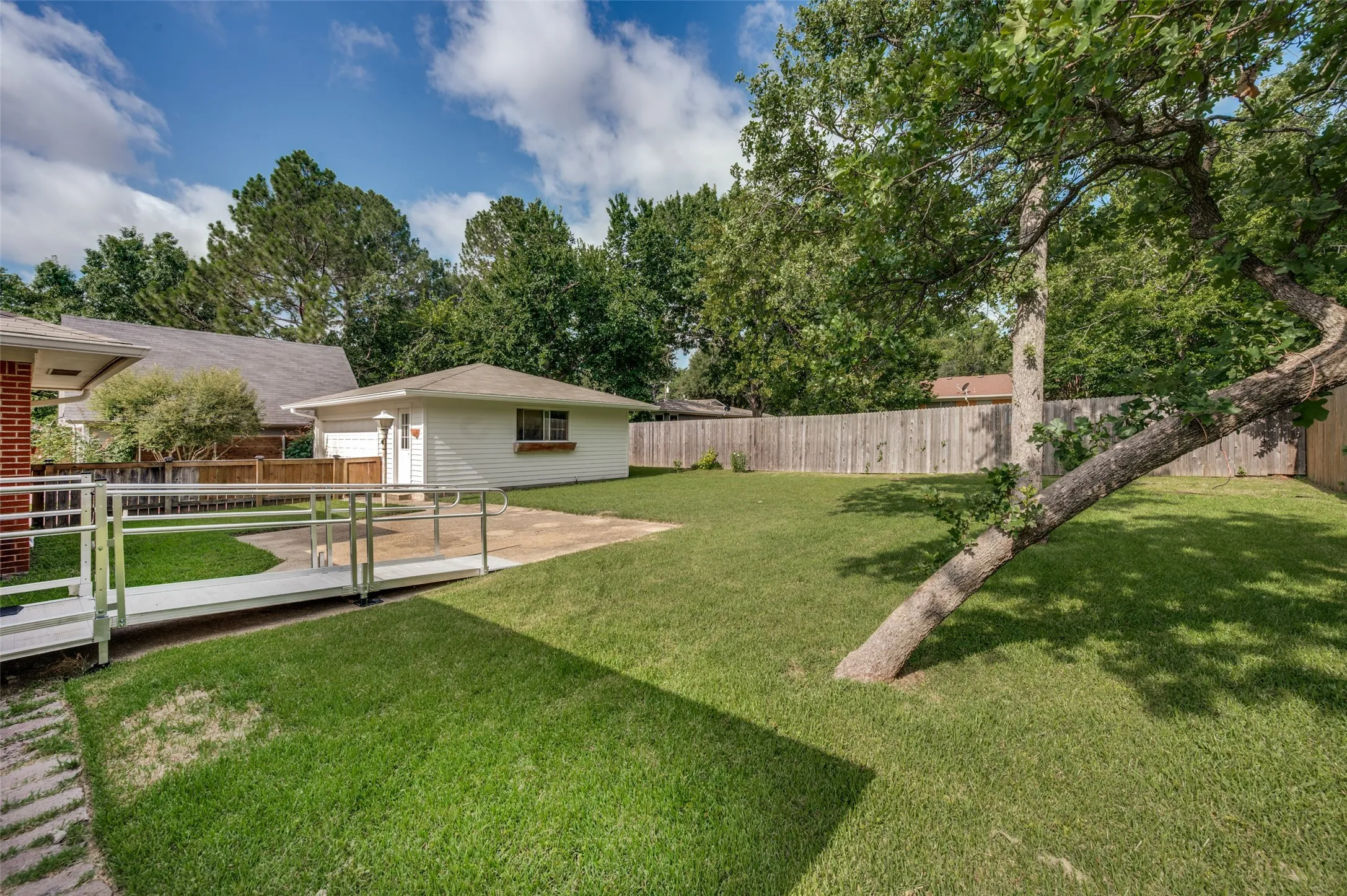This backyard has it all: large green space, shade trees, a concrete patio, a privacy fence and access to the combination garage and workshop.