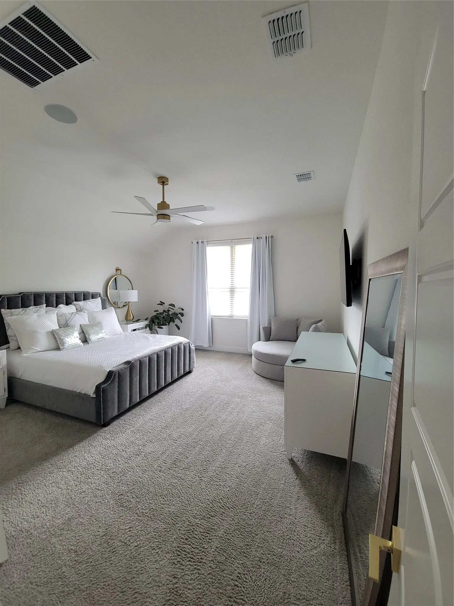 Large private primary suite includes Stylish wall mounted bedside mirrors plus blackout drapes or natural sunlight with modern remote control ceiling fan
