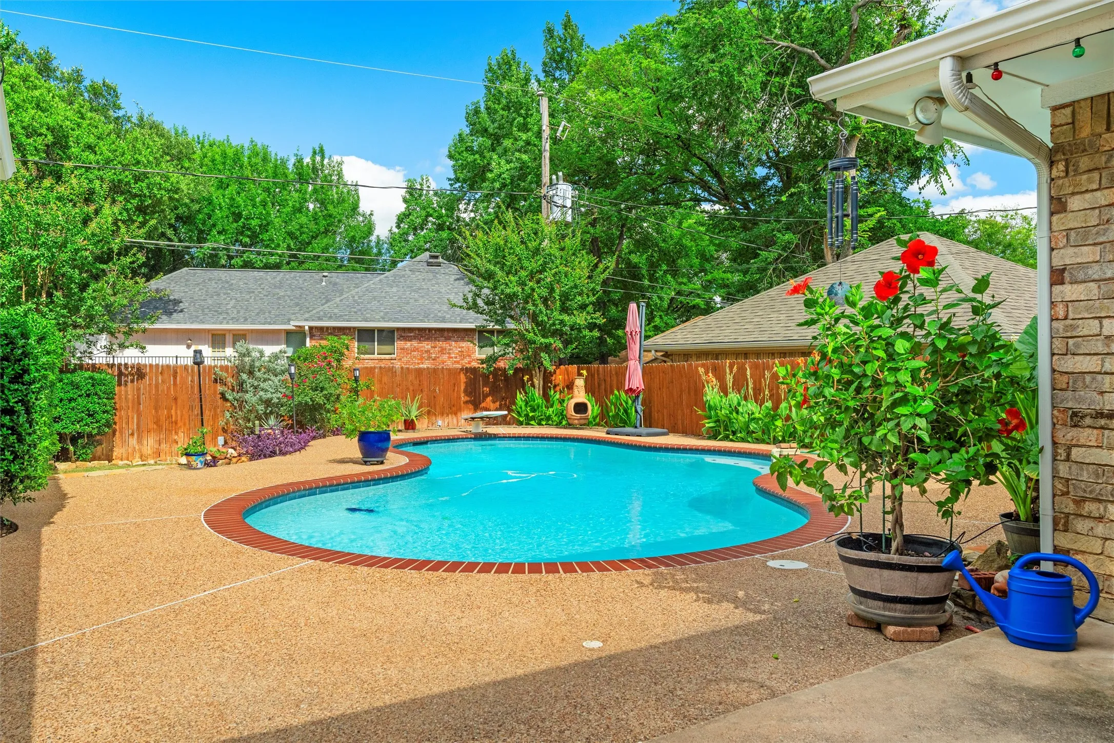 Freestyle swimming pool with brick coping, surrounded by an exposed aggregate patio