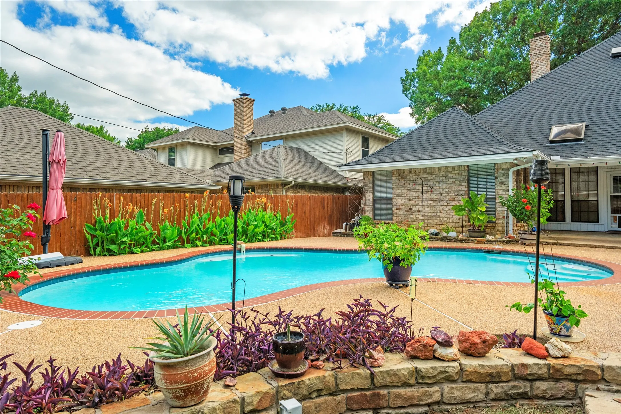 Curved swimming pool with a stone coping and textured concrete surround