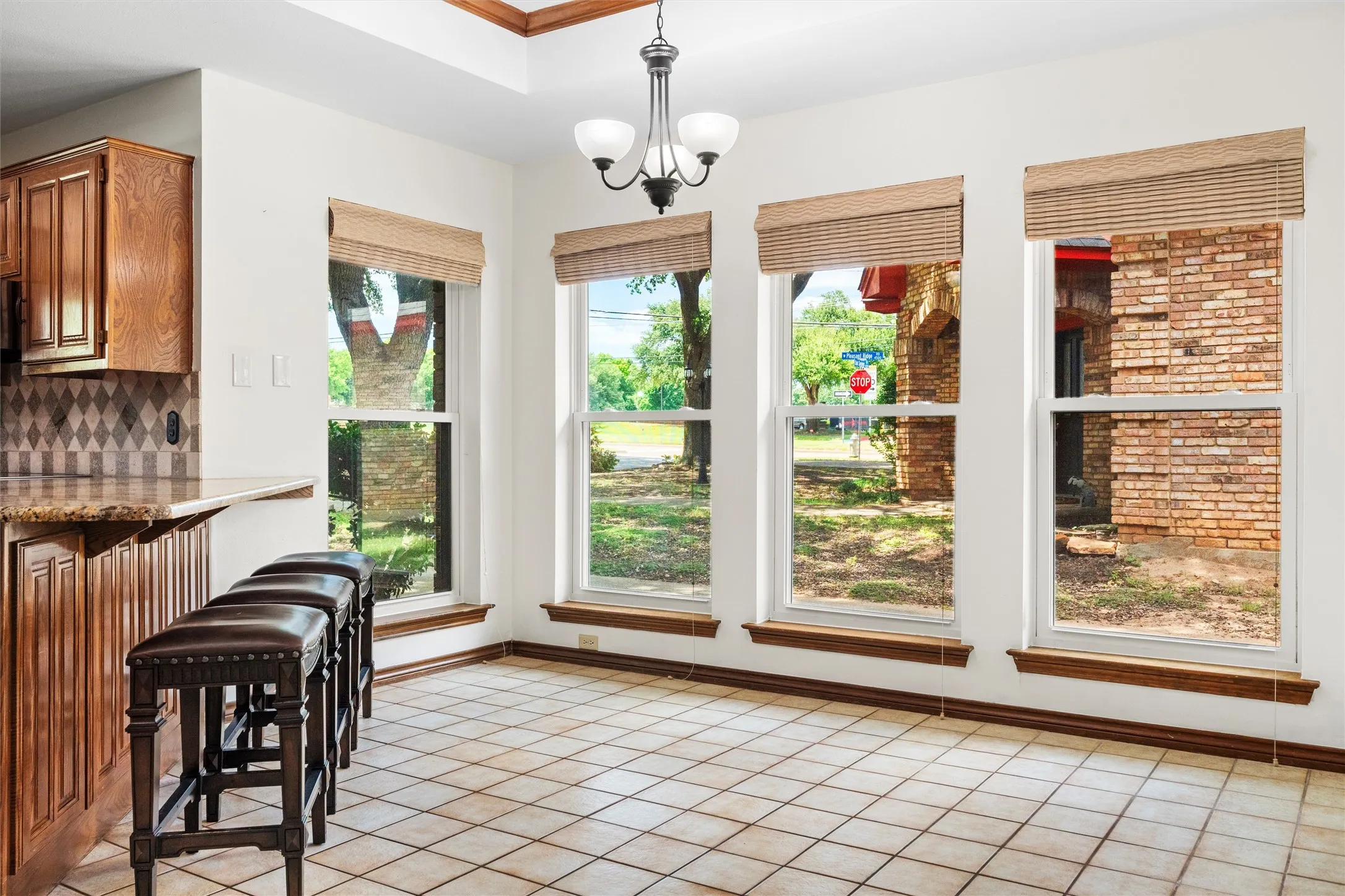 Dining area featuring a three-light chandelier, a coffered ceiling with wood-finish trim, and four large windows with woven shades