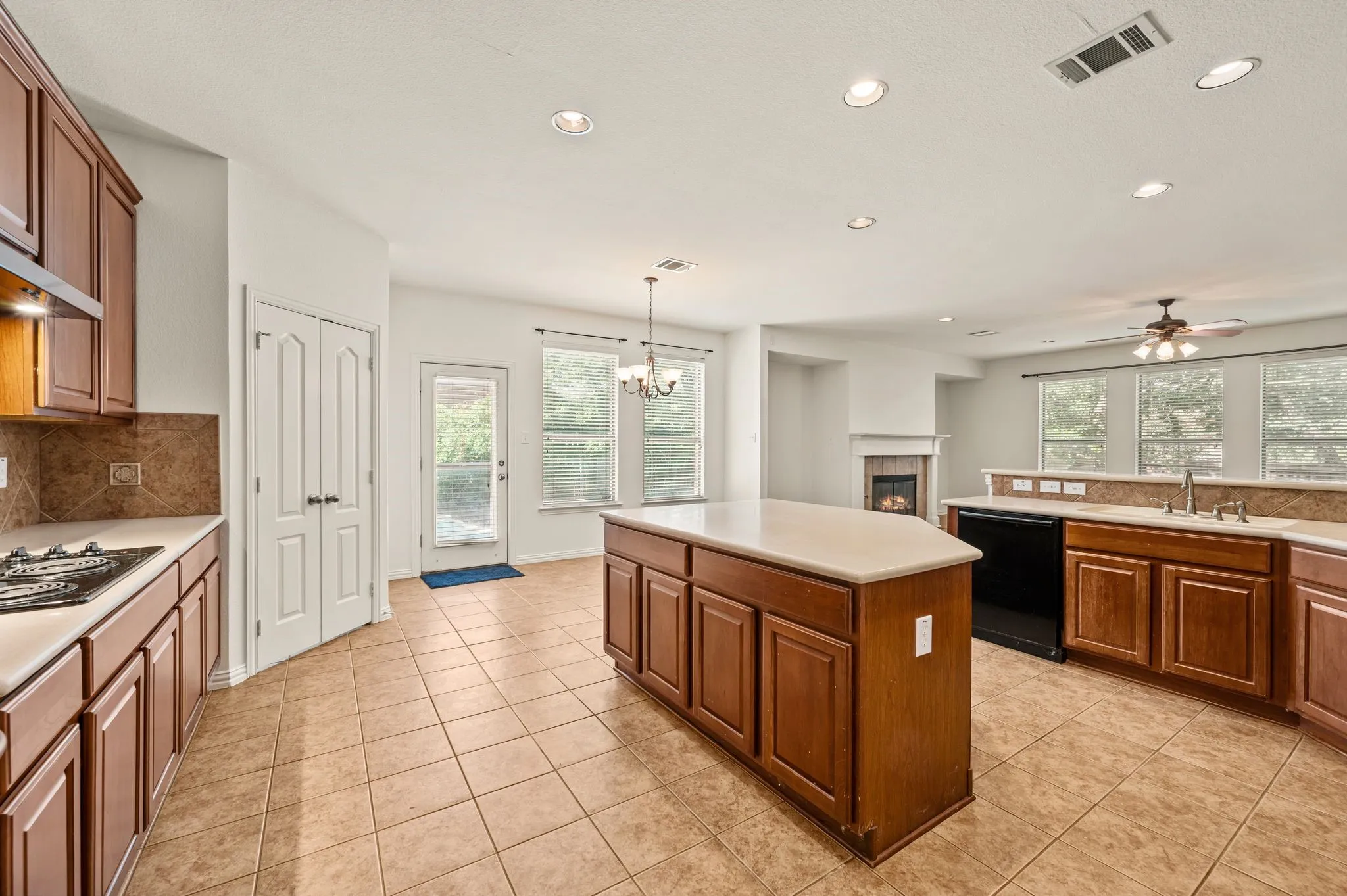Spacious kitchen featuring a central island, recessed lighting, tile flooring, rich wood-finish cabinetry, and a gas cooktop