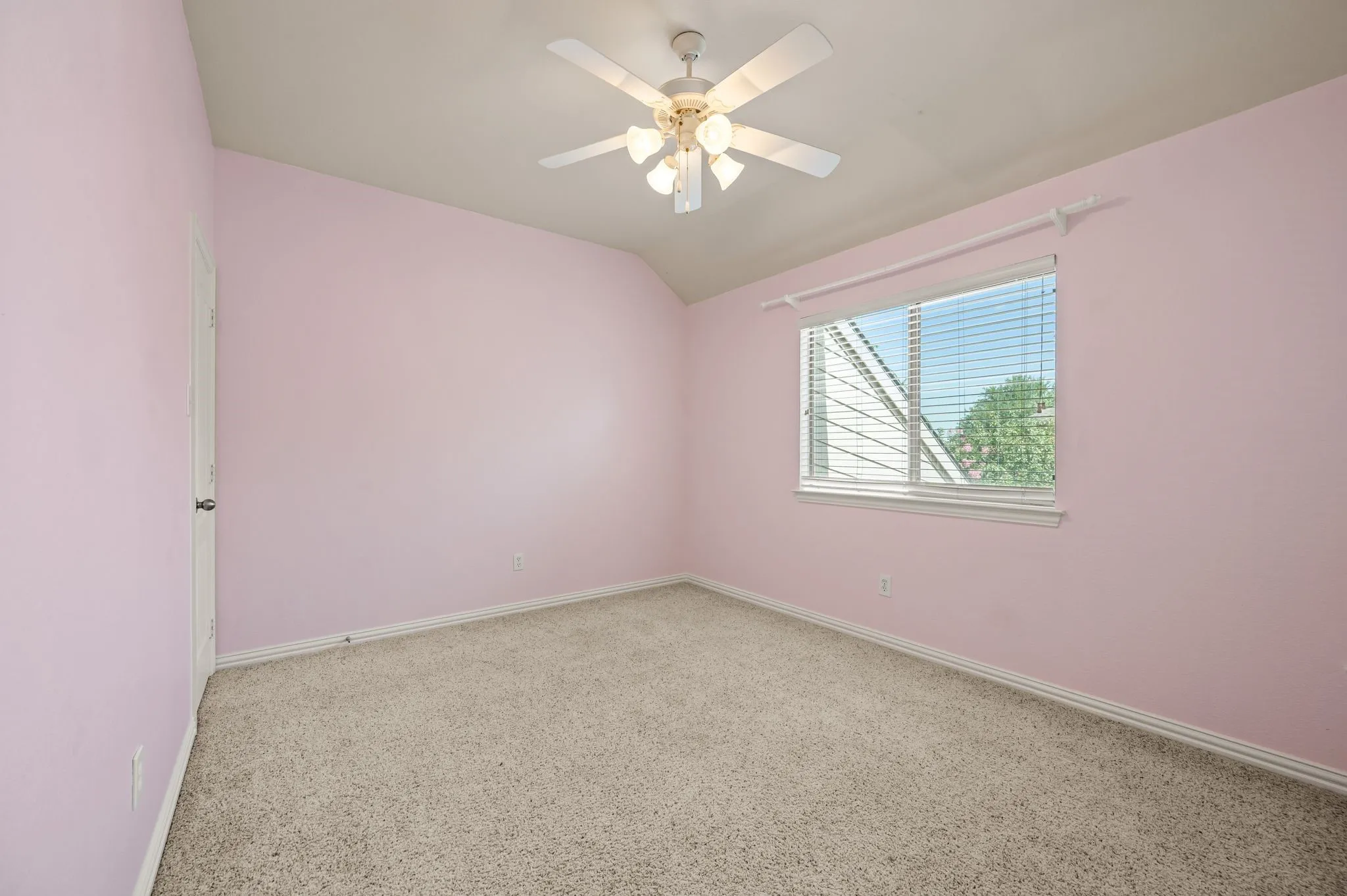 Spacious room featuring neutral carpet, a single window with blinds, and an overhead ceiling fan with integrated lighting