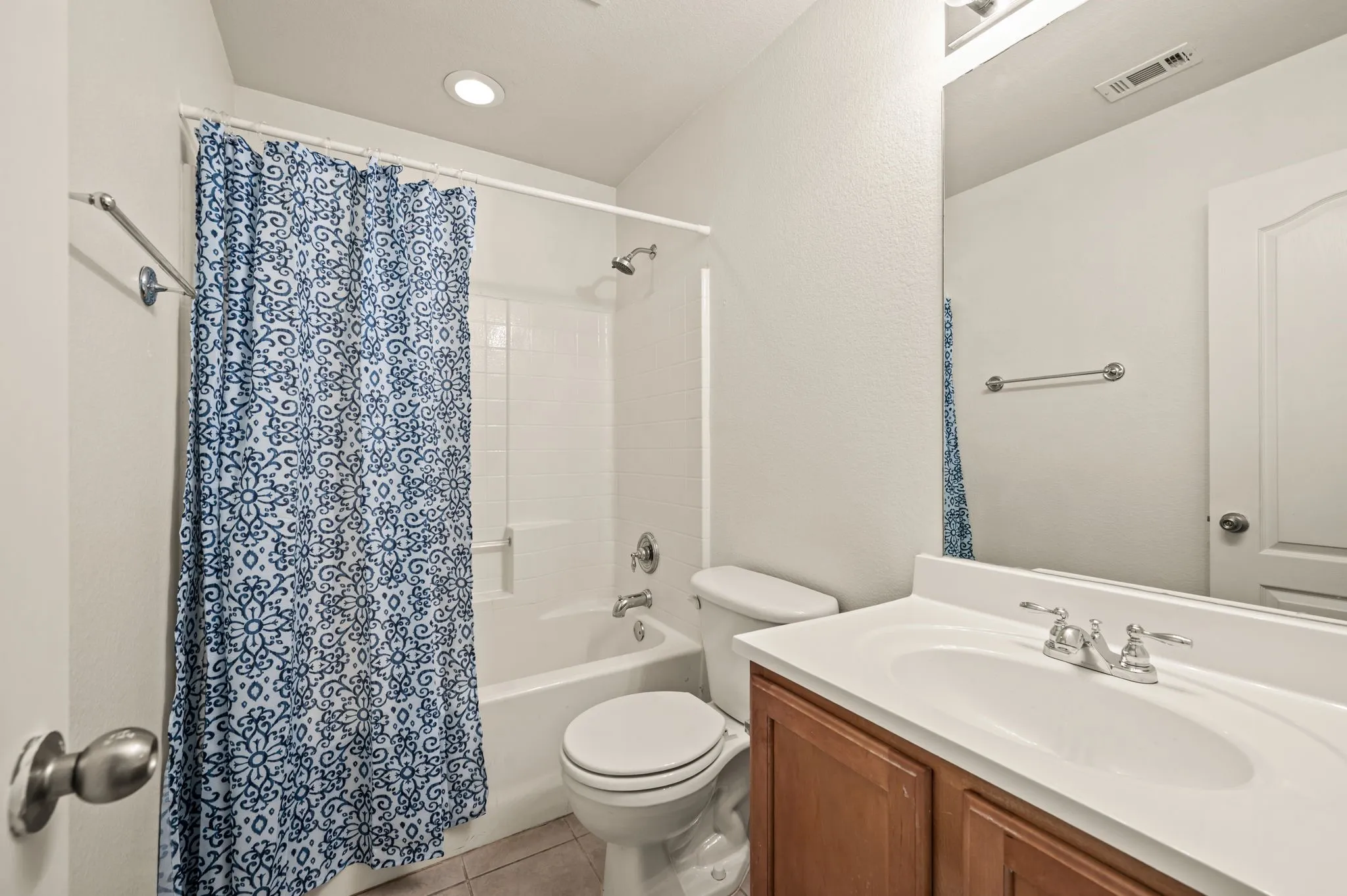 Full bathroom featuring a single vanity with wood-finish cabinetry, a white countertop, and a built-in sink