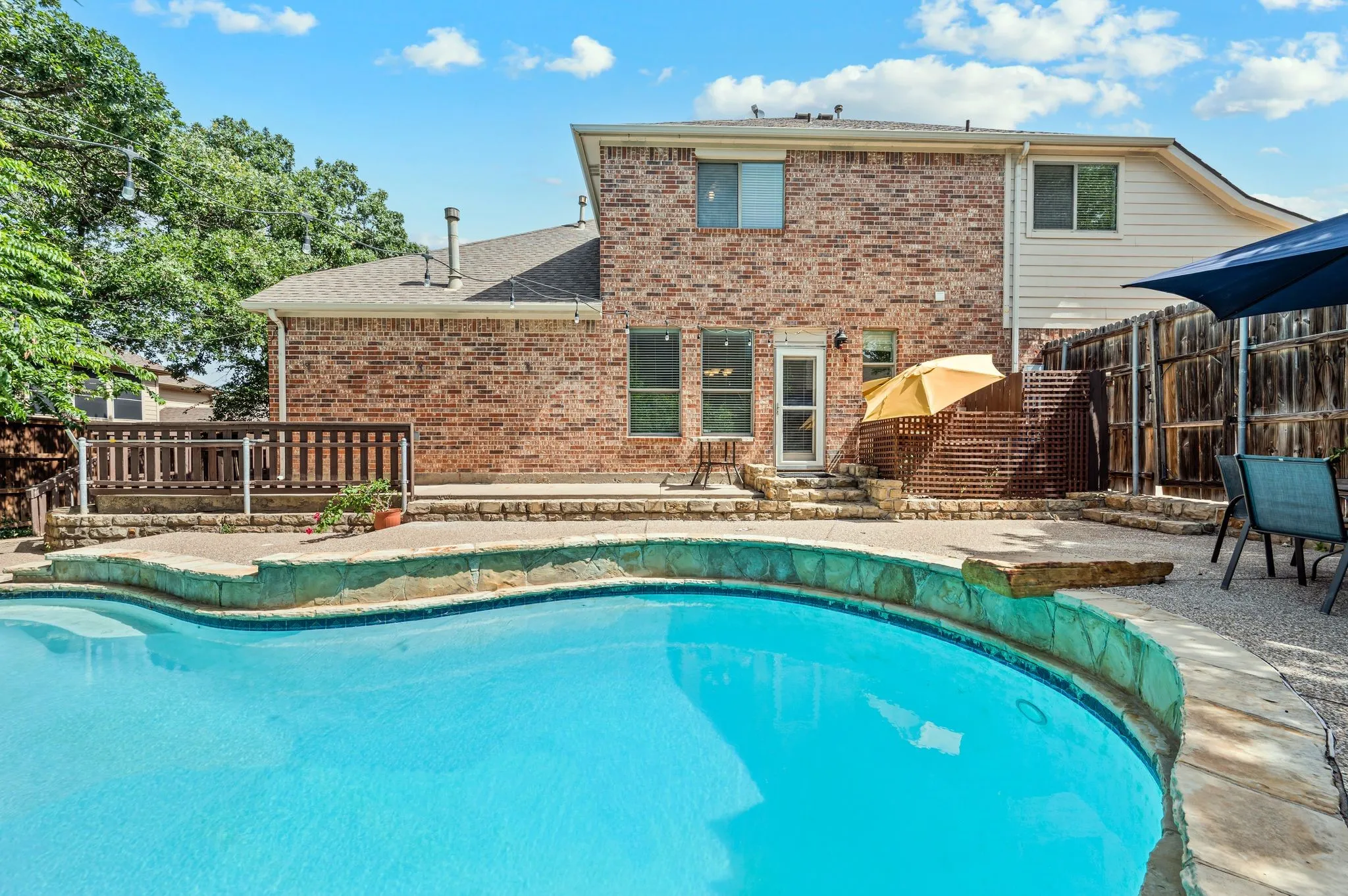 Brick exterior featuring a multi-level patio with a built-in swimming pool