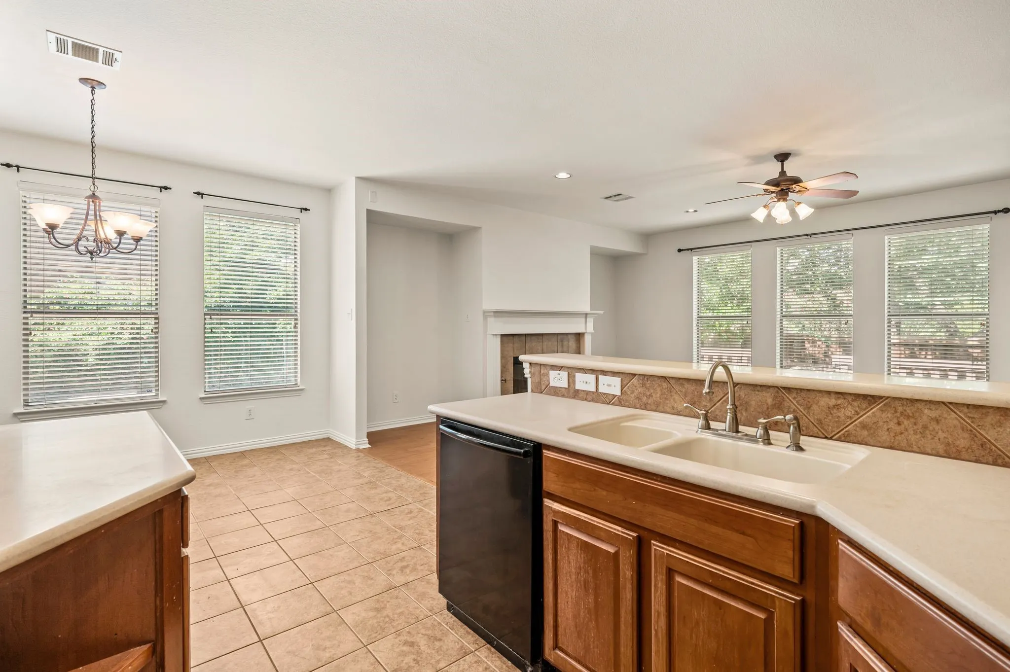 Kitchen featuring a double basin sink, light-toned countertops, wood cabinetry, and a tile backsplash