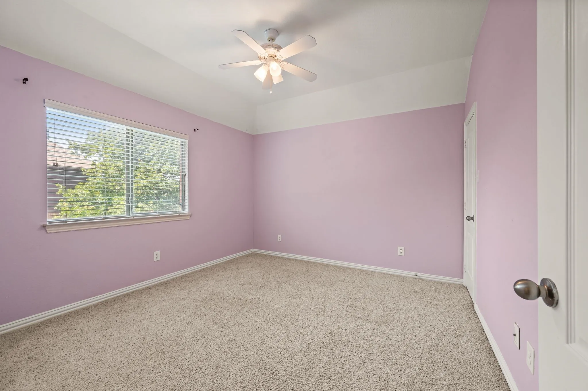 Carpeted room featuring a ceiling fan, a window with horizontal blinds, and a white interior door
