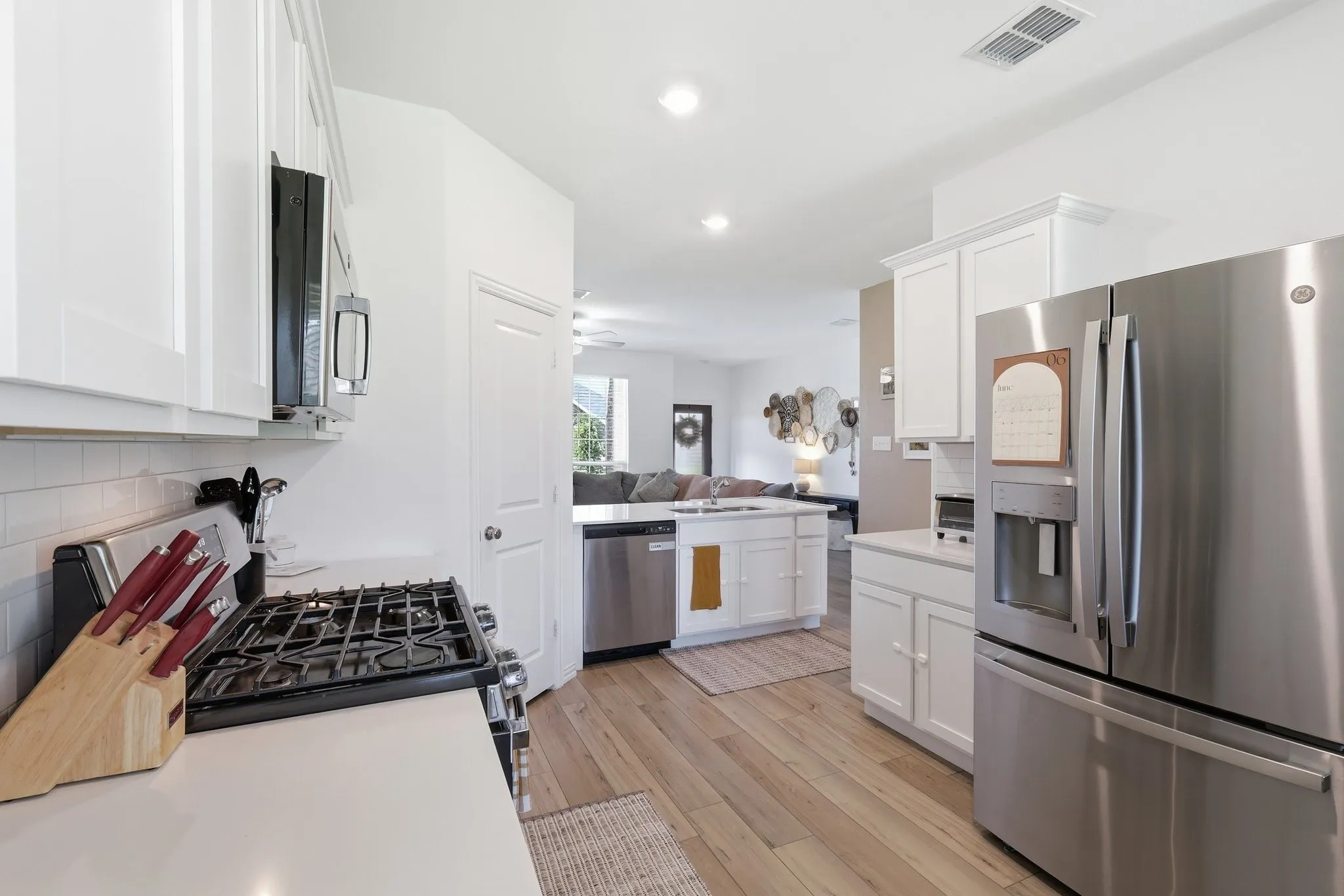 Contemporary kitchen featuring white cabinetry, stainless steel appliances, light wood-finish flooring, and white countertops