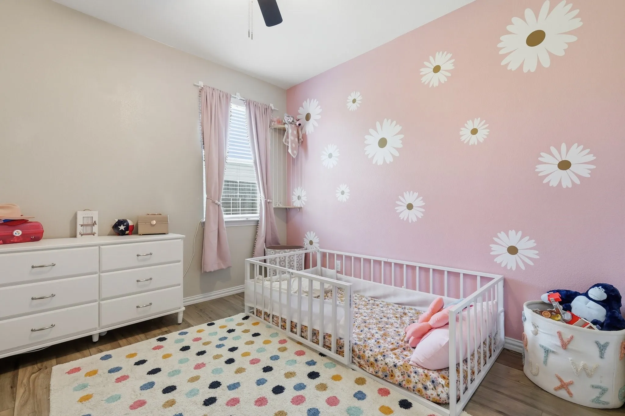 Room featuring wood-finish flooring, a ceiling fan, and a window with blinds and drapes