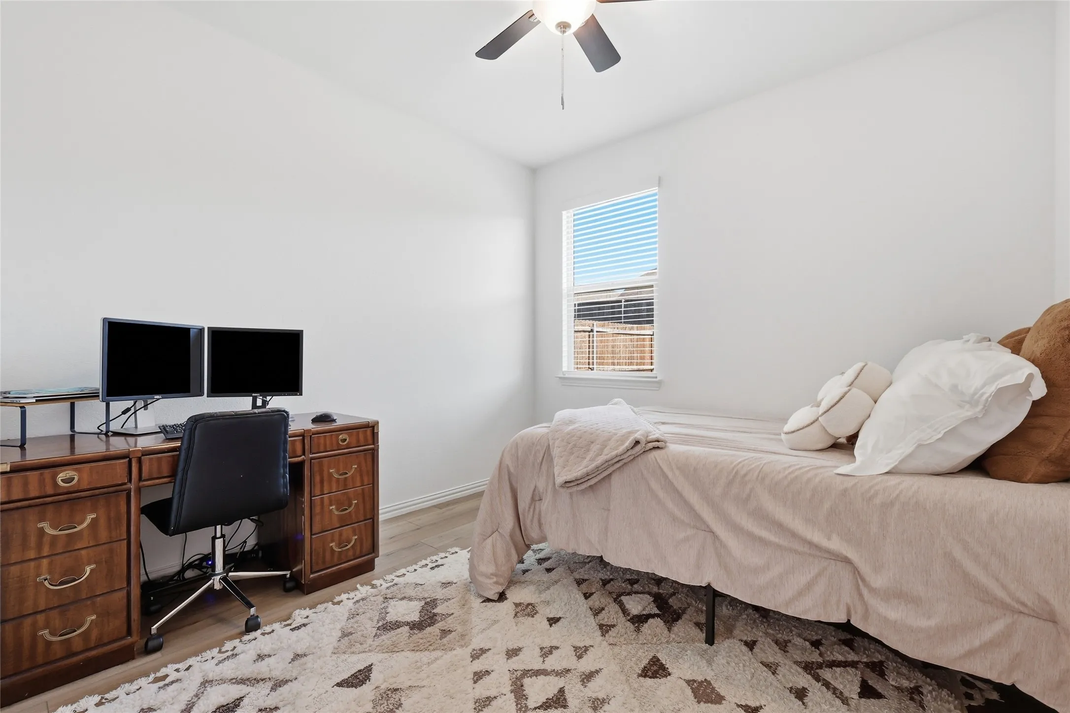 Bright room featuring neutral wall tones, wood-finish flooring, a window with horizontal blinds, and a ceiling fan with light
