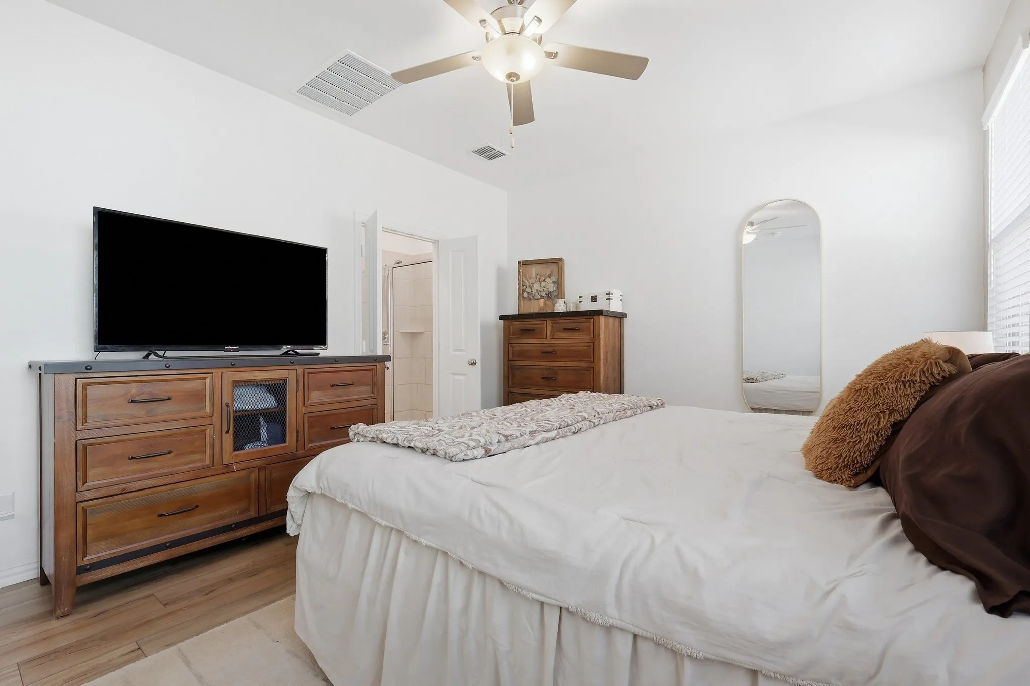 Spacious room featuring wood-finish flooring, a ceiling fan, and a window with horizontal blinds