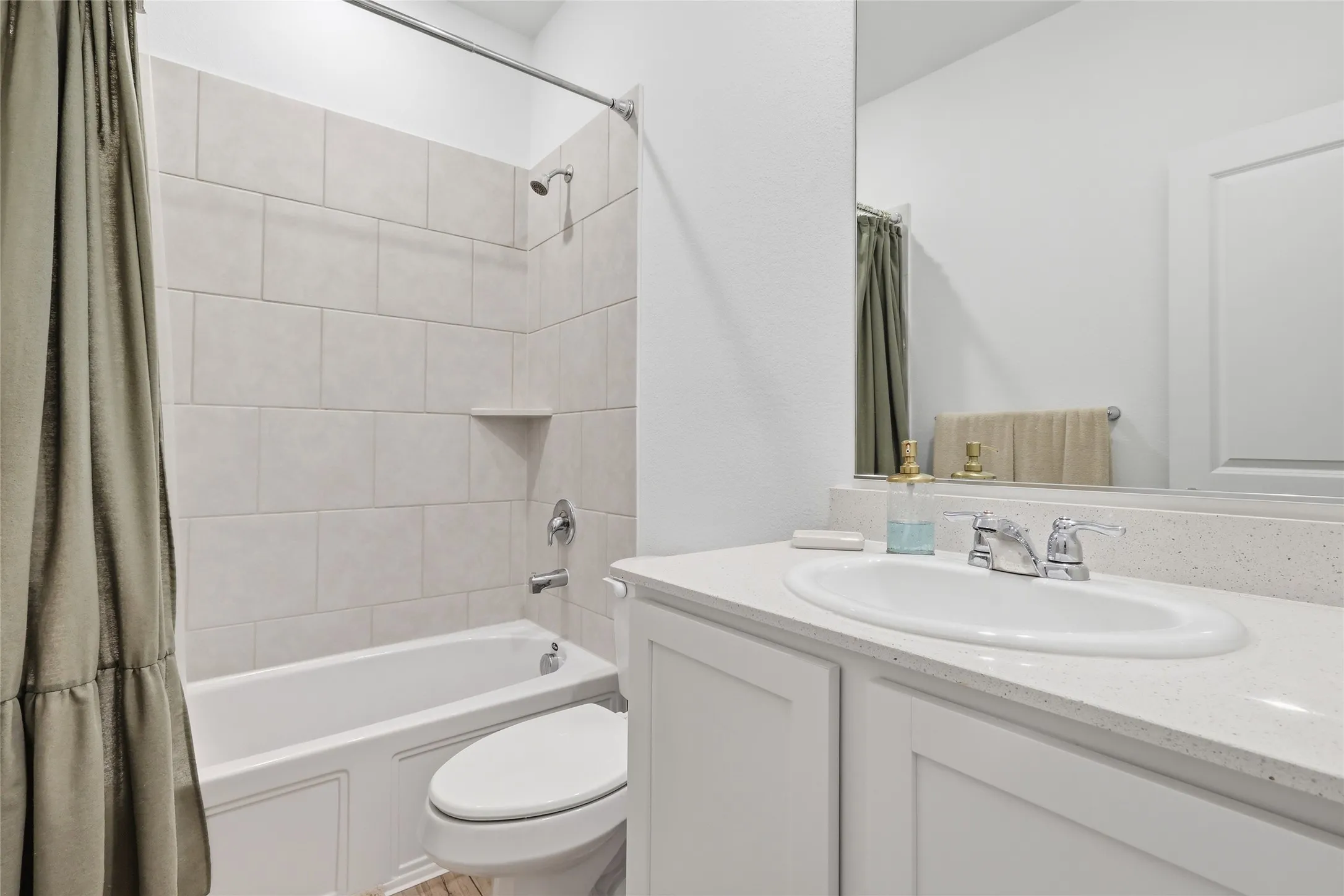 Bathroom featuring a white bathtub with subway tile surround, chrome fixtures, and a corner shelf