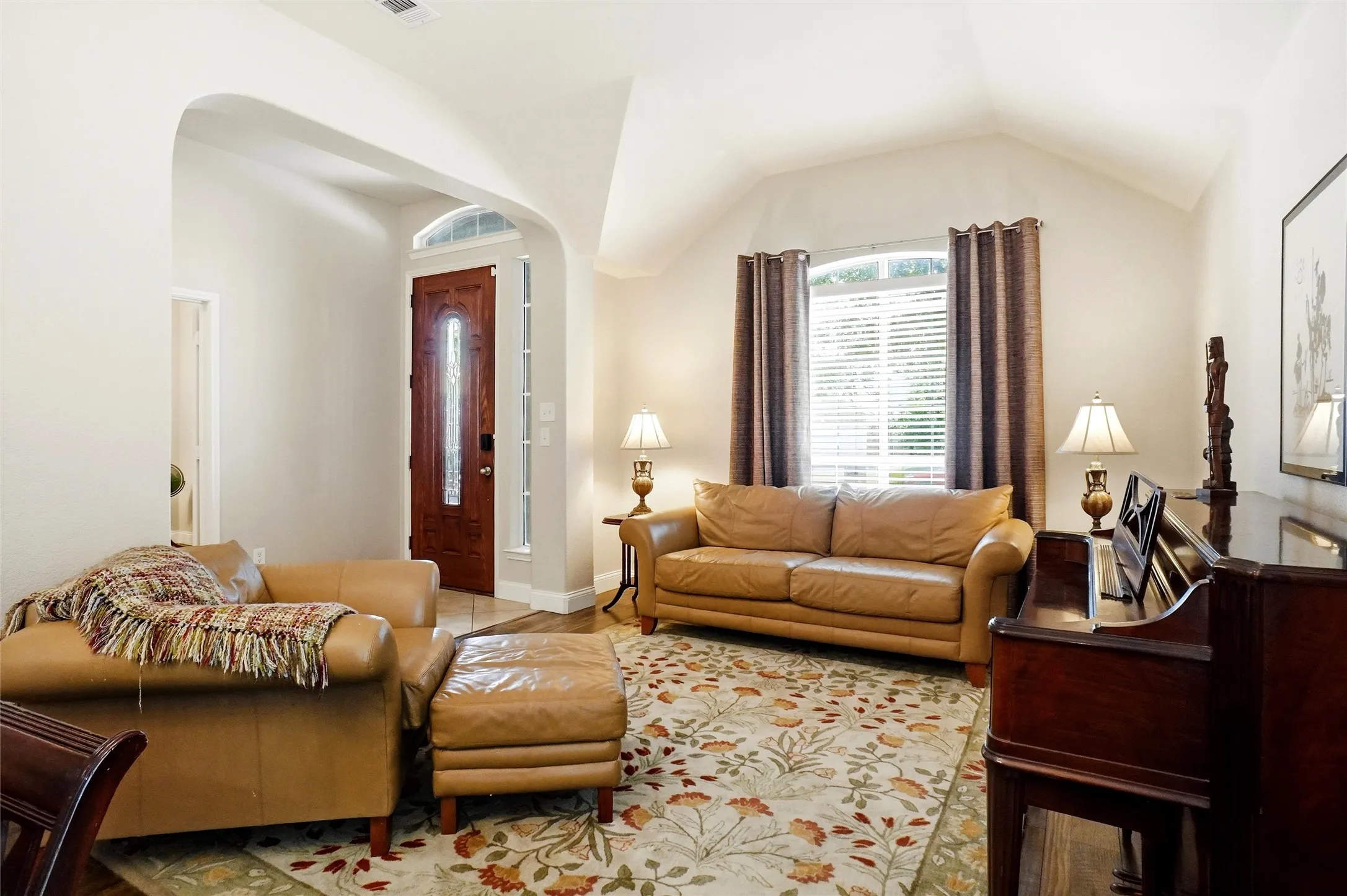 Entryway featuring a wood-panel door with decorative glass, arched transom, and sidelights