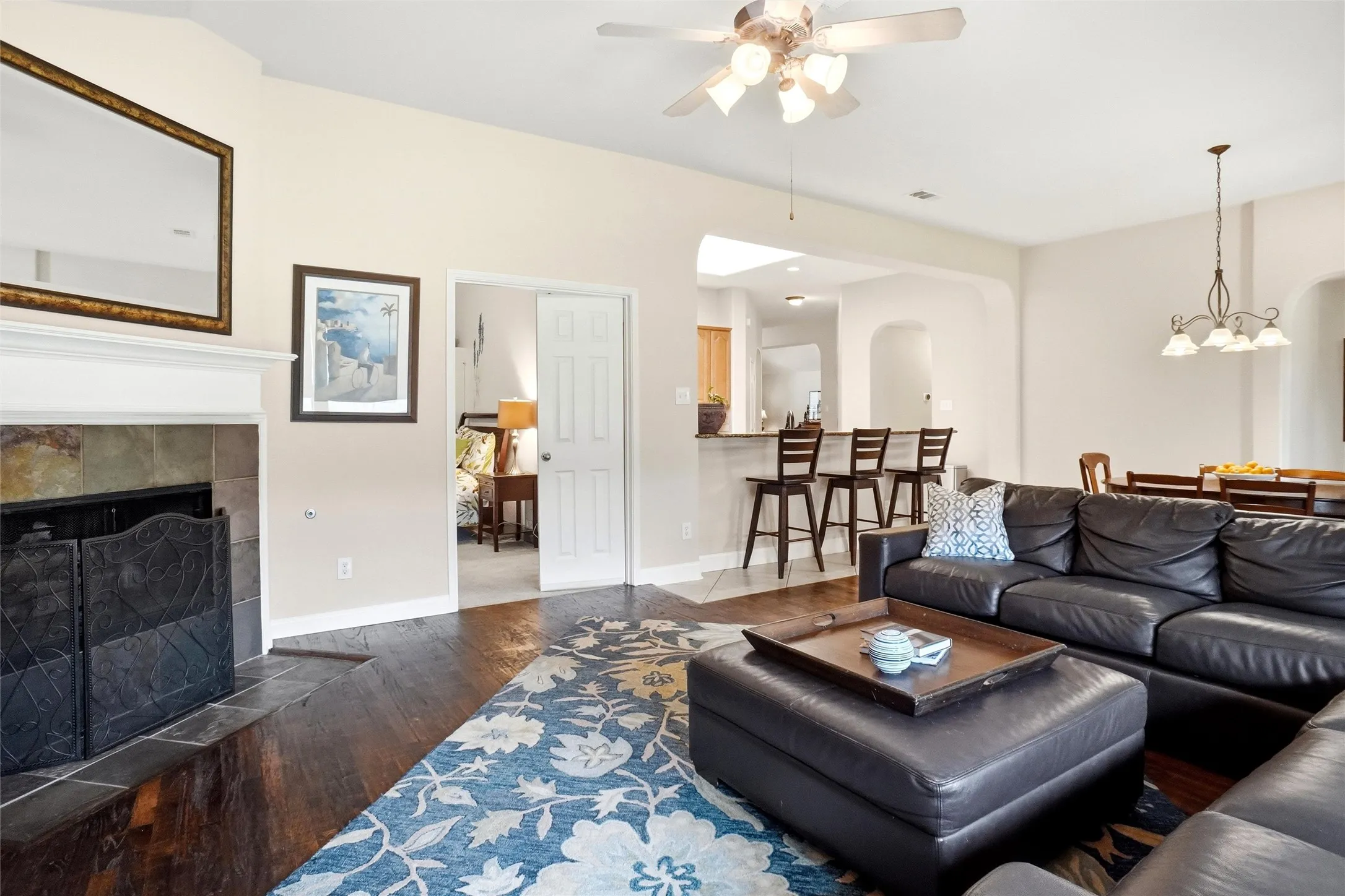 Living area featuring wood-finish flooring, a vaulted ceiling, and a fireplace with a stone surround and white mantel