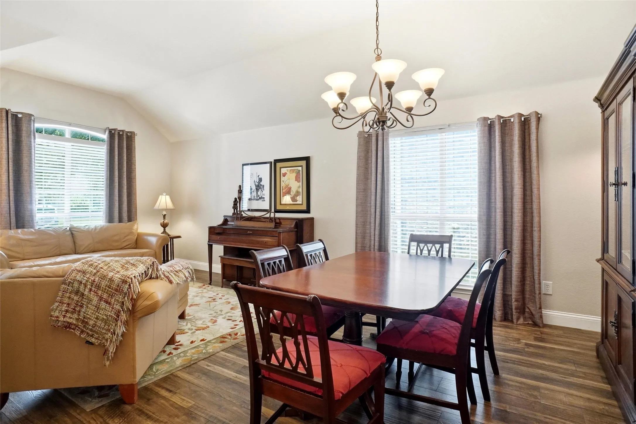 Dining area featuring wood-finish flooring and a central chandelier with frosted glass shades