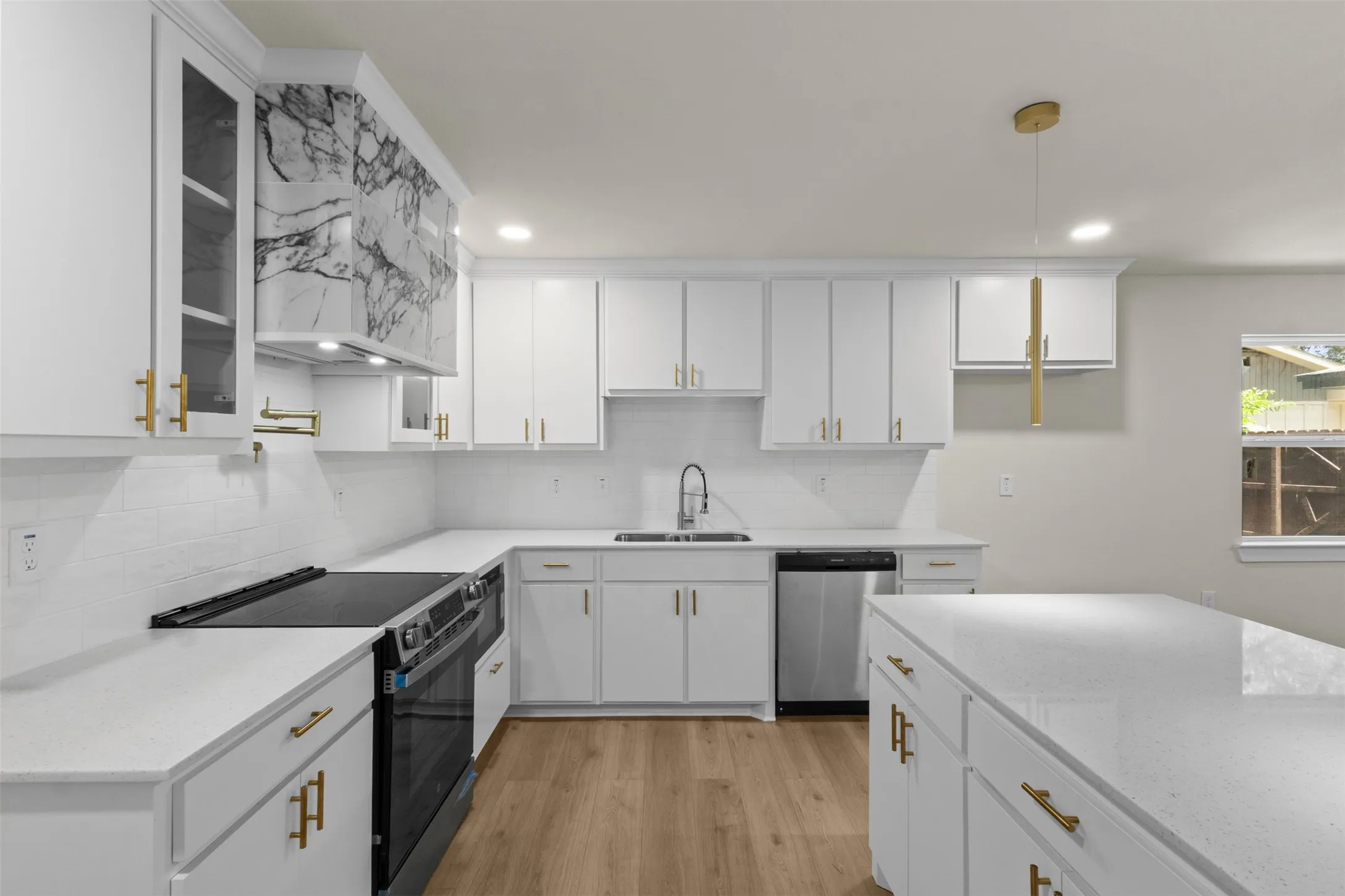 Contemporary kitchen featuring white cabinetry, quartz countertops, and gold-tone hardware