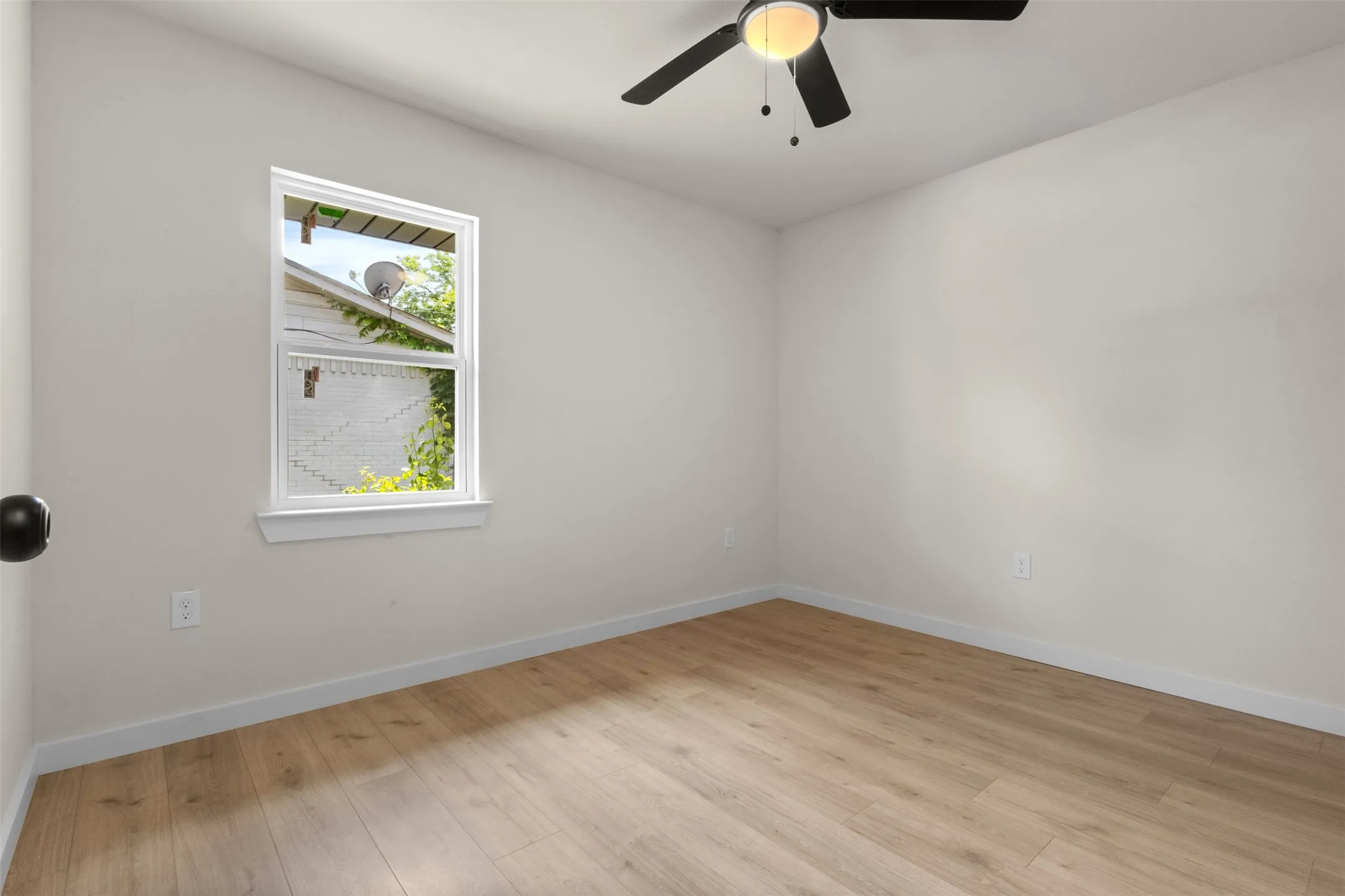 Room featuring light wood-finish flooring, a white trim baseboard, and neutral painted walls