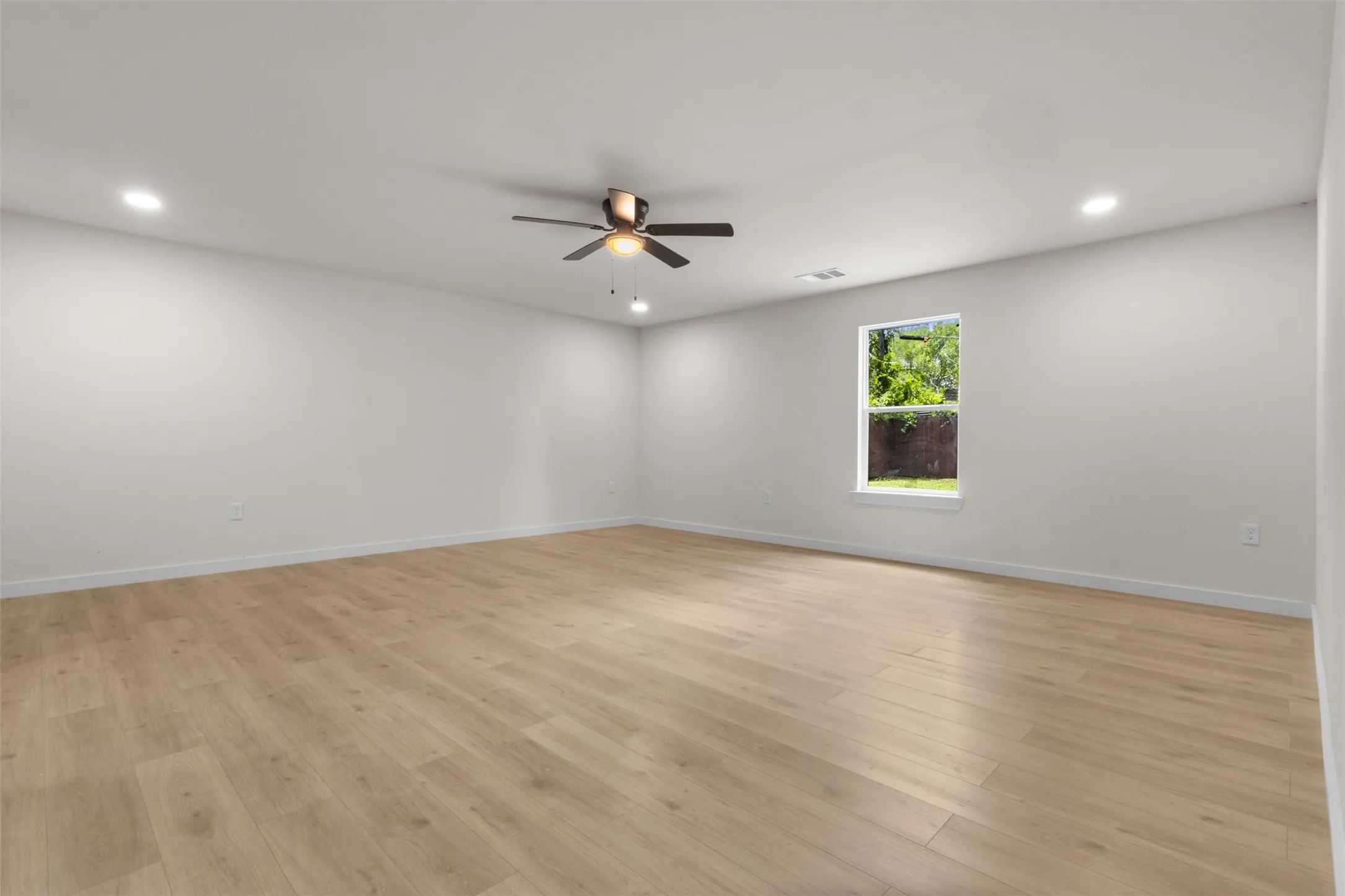 Spacious interior room featuring light wood-finish flooring