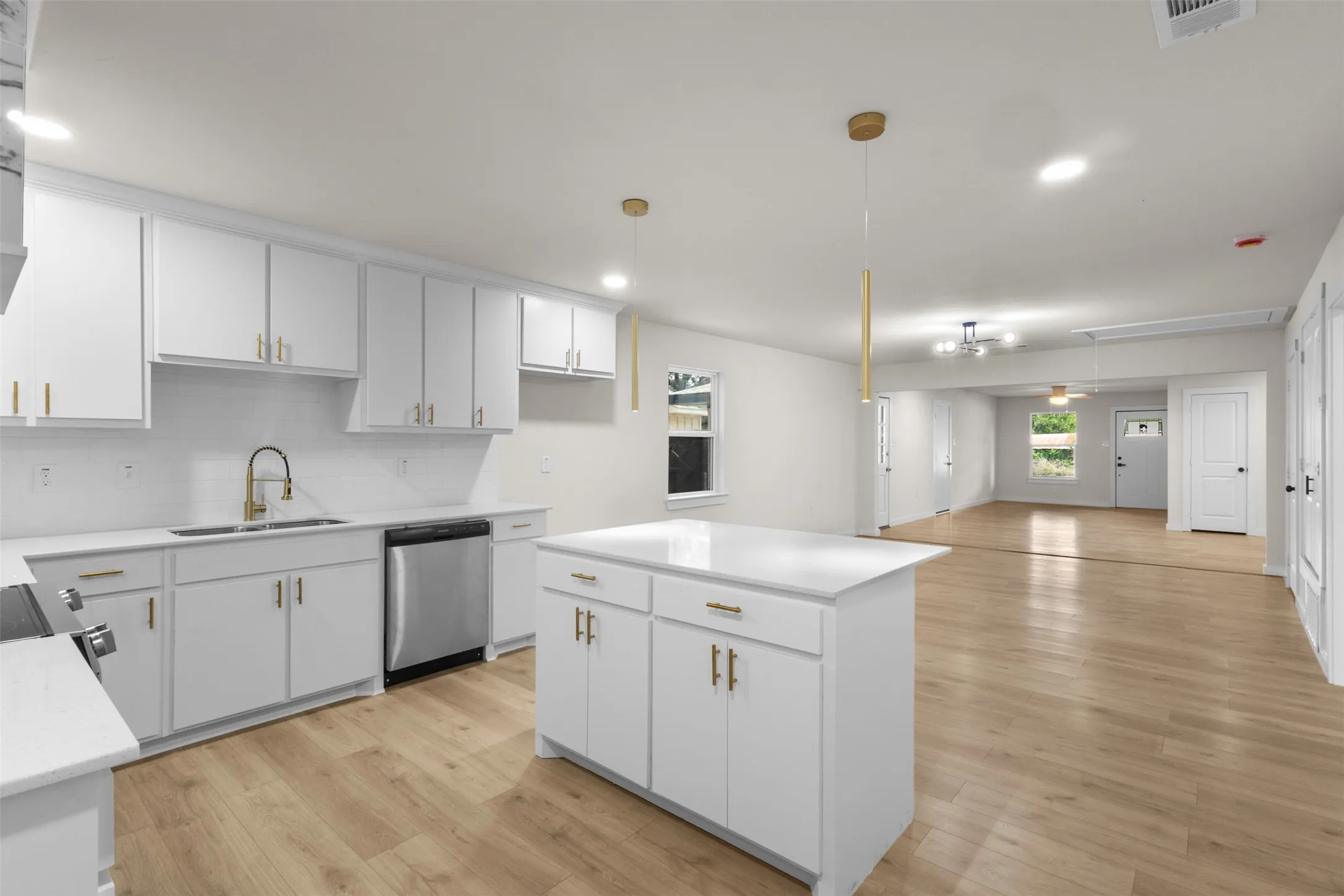 Modern kitchen featuring white cabinetry, a central island with countertop, wood-finish flooring, and stainless steel appliances