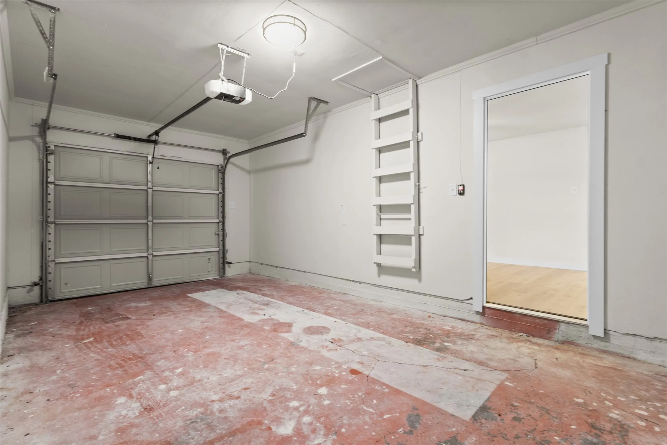 Garage interior featuring a sectional garage door, overhead lighting, and an automatic garage door opener
