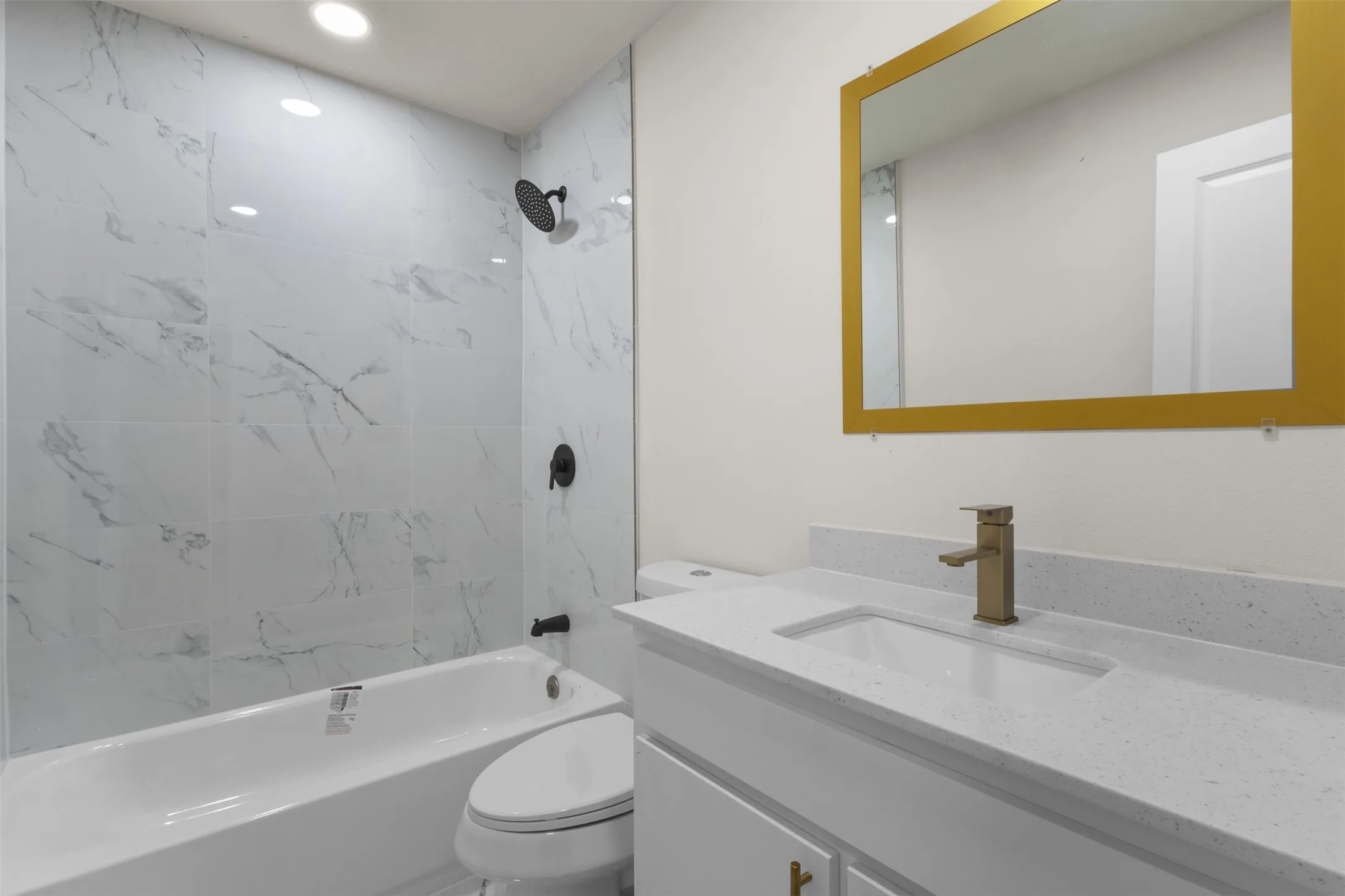Bathroom featuring a white vanity with an integrated rectangular sink, speckled countertop, and brushed gold faucet