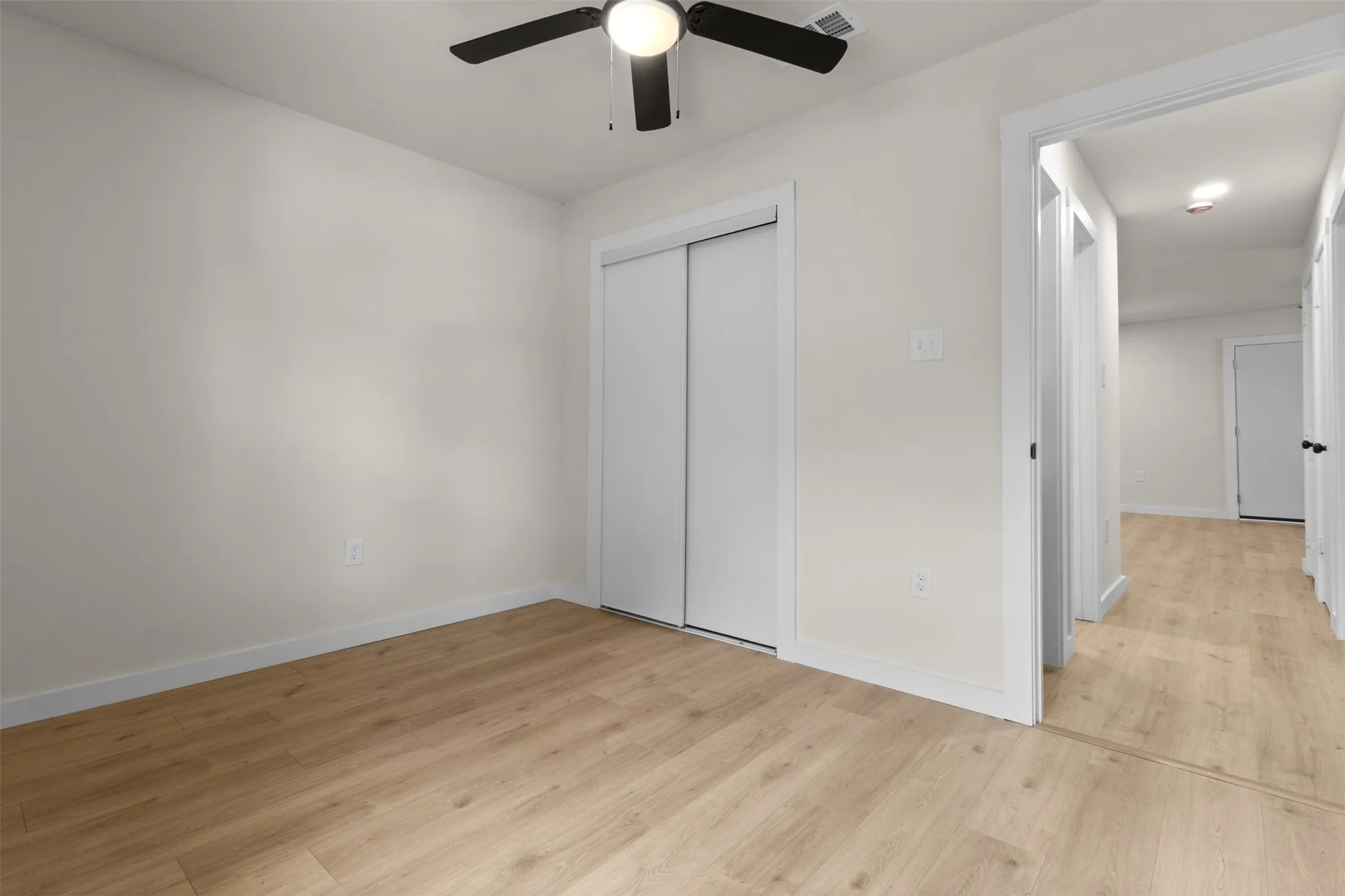 Bedroom featuring a ceiling fan with integrated lighting, wood-finish flooring, and light-toned wall paint