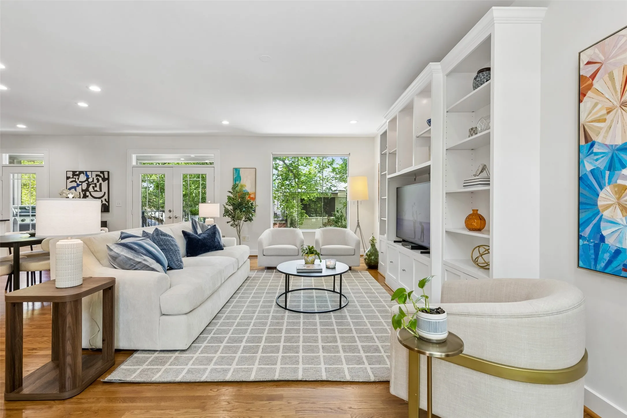 Spacious living area featuring rich wood-finish flooring, recessed lighting, and a built-in entertainment center with extensive shelving