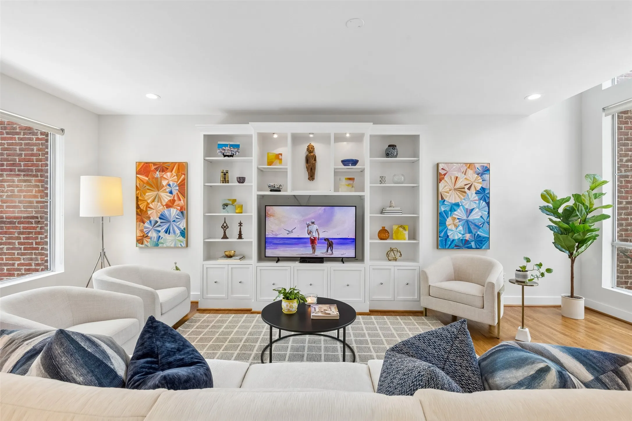 Living area featuring a floor-to-ceiling custom built-in media console with open shelving and lower cabinetry