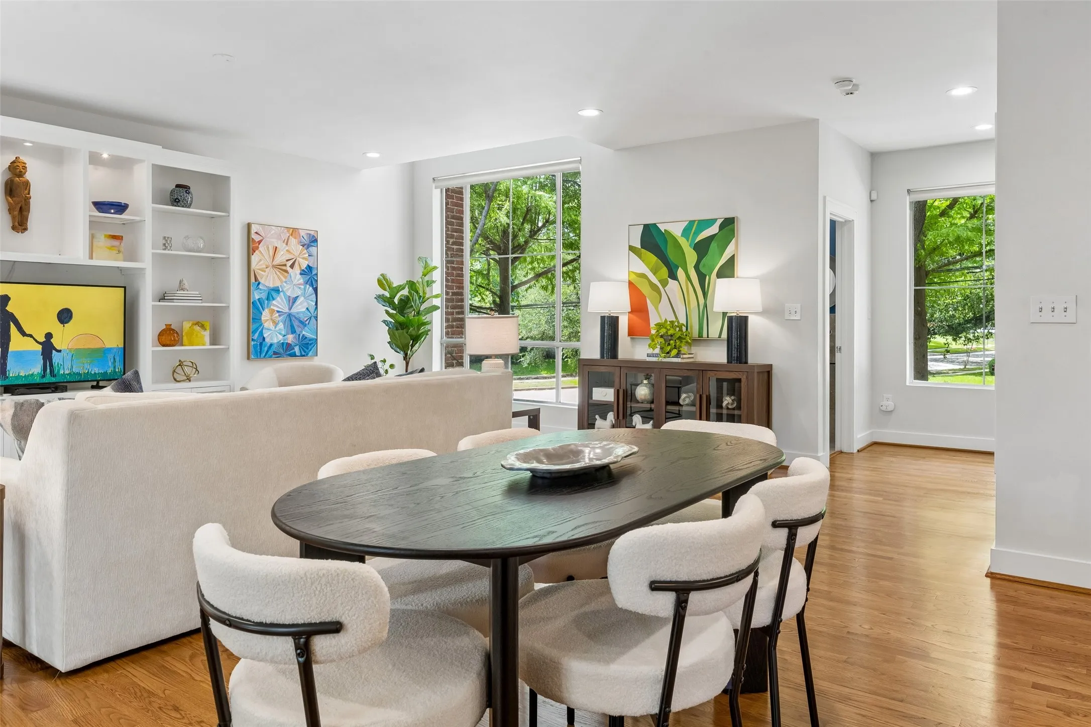 Open-concept living space with wood-finish flooring, recessed lighting, and large windows